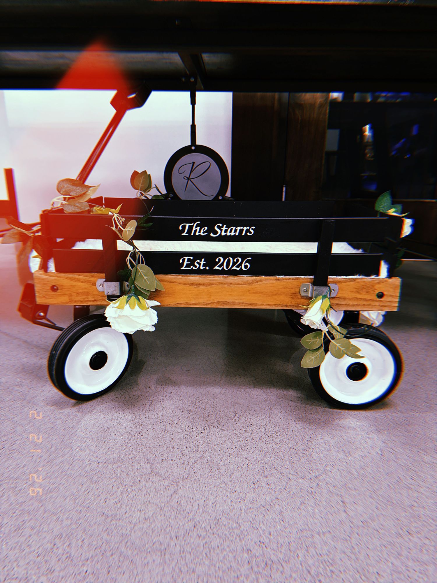 A wooden wagon with white wheels and personalized text 'The Starrs Est. 2026' displayed on its side.