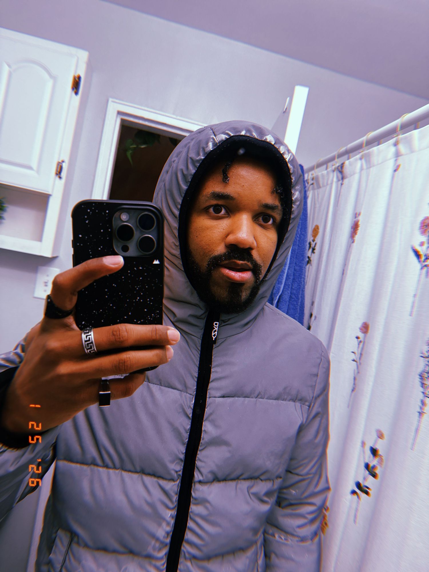 A series of four similar selfie photos showing someone in a gray hoodie holding a phone in front of a mirror.