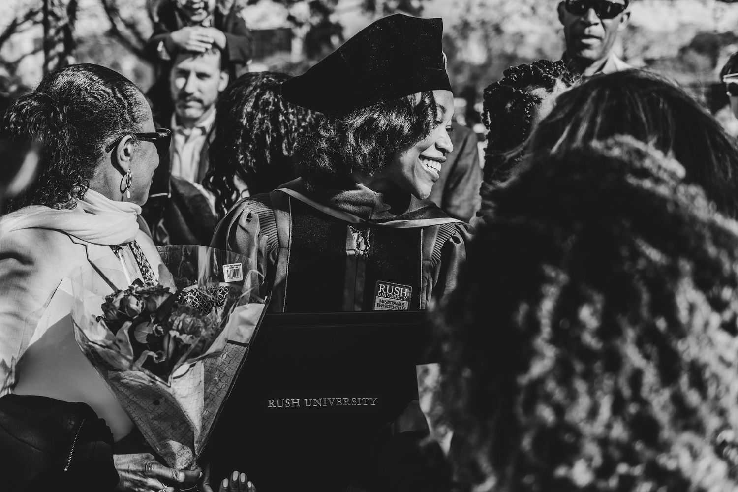 A crowd of people at a concert or event cheer and dance together in black and white photography.