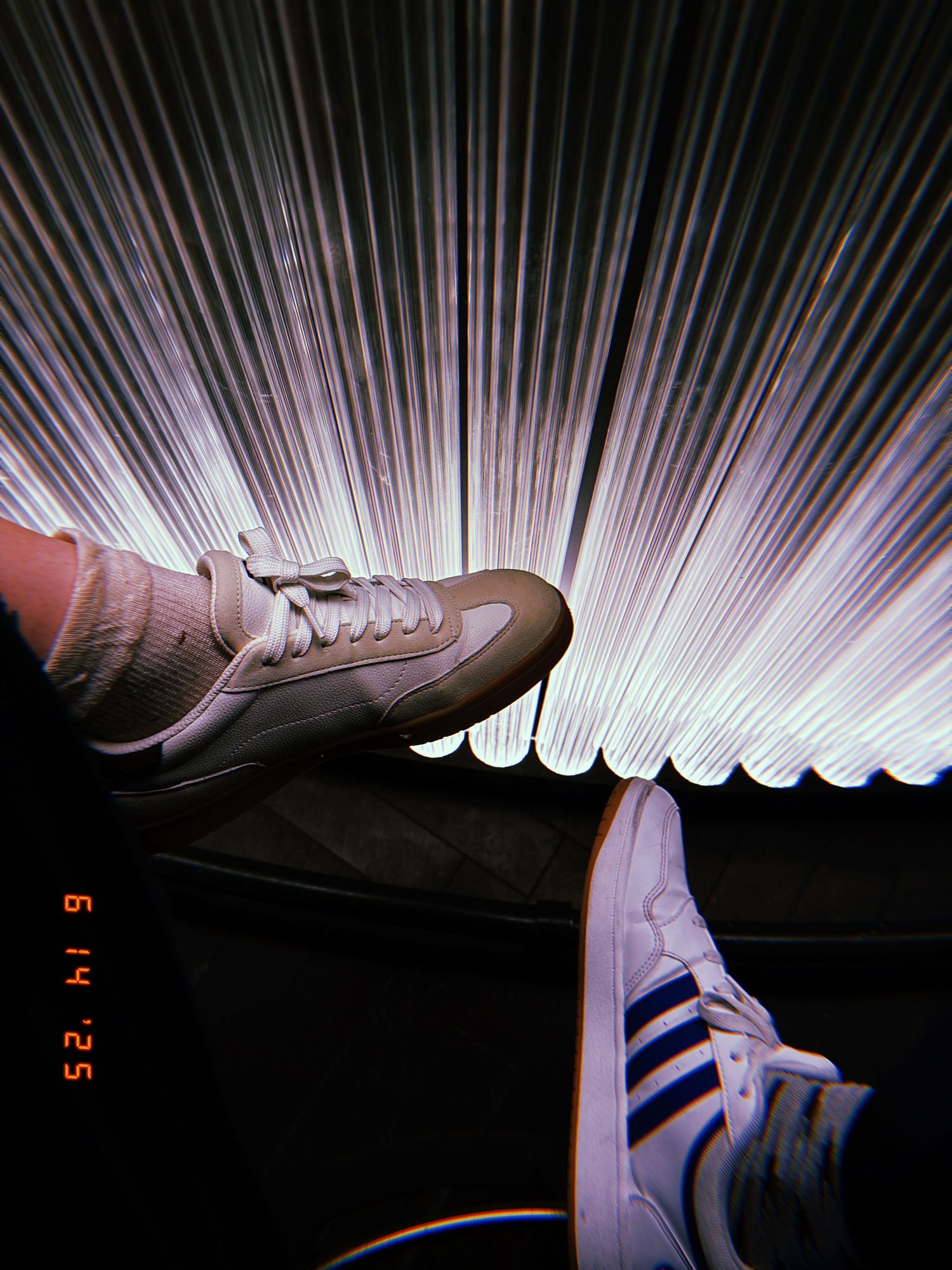 Two athletic shoes illuminated against dark background with striking white light rays creating dramatic effect.