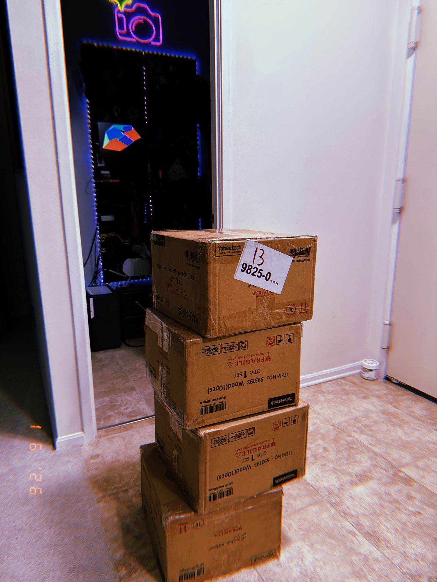 Stack of brown cardboard moving boxes placed against a white wall in a room with beige flooring.