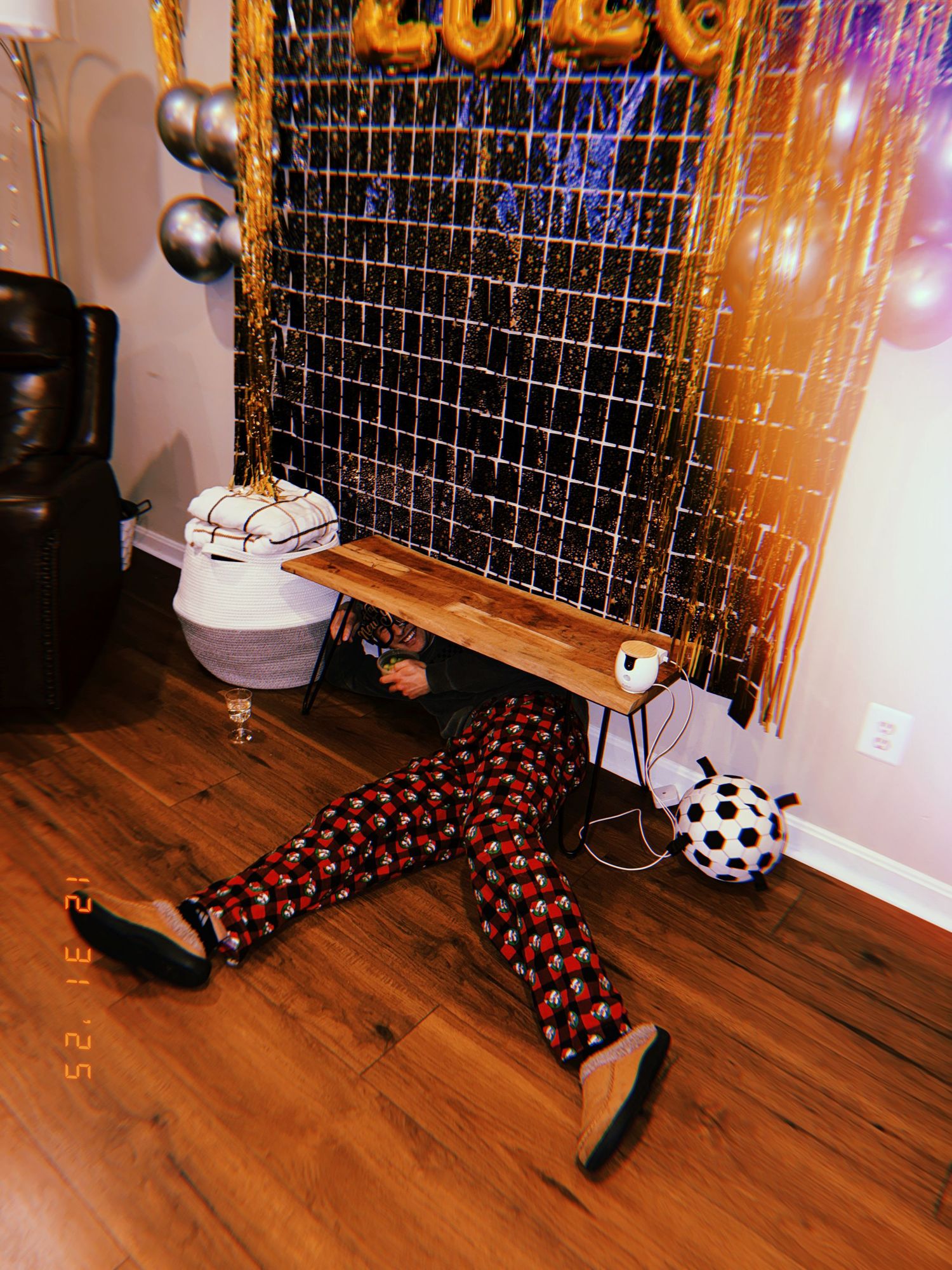 A sequence of photos showing a soccer ball rolling across a wooden floor past a glowing string light display.