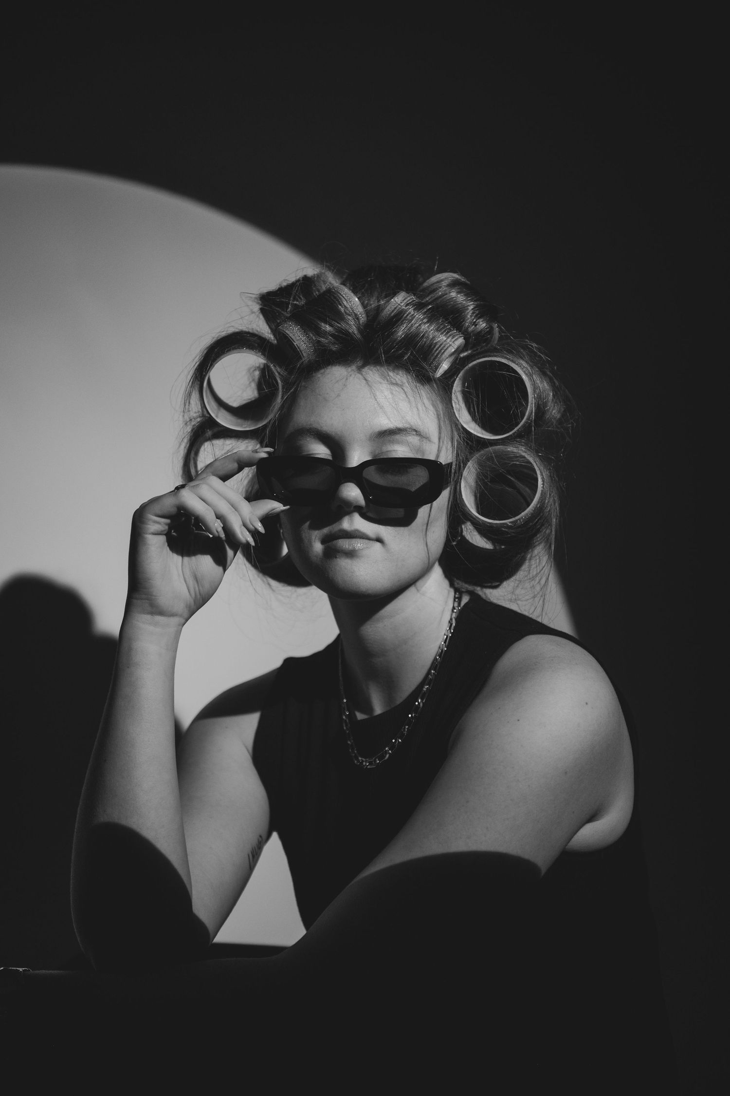 Artistic black and white photo series showing someone holding up dark round objects to their eyes in a playful manner.