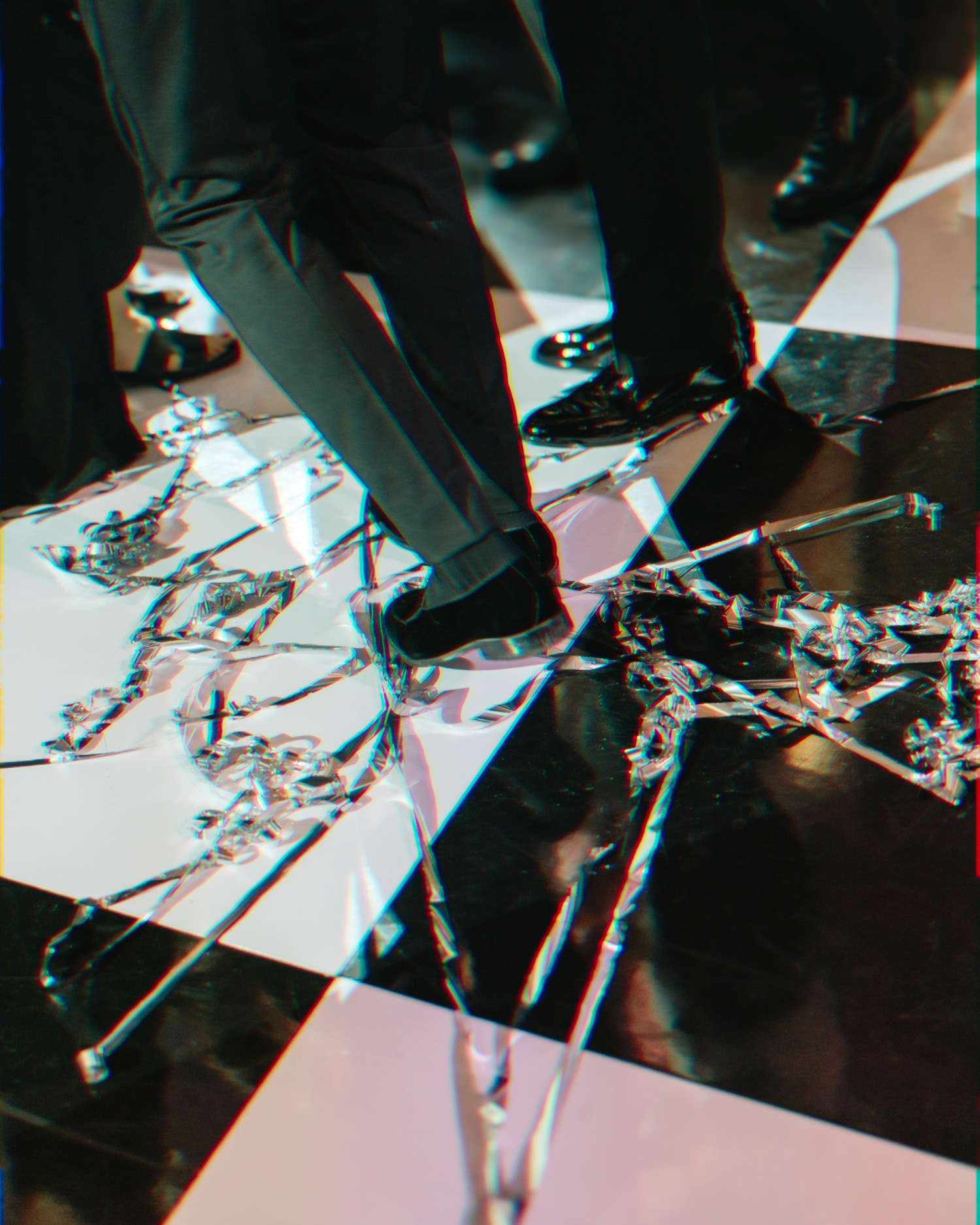 Close-up view of dress shoes walking on a reflective black and white surface with dramatic lighting.