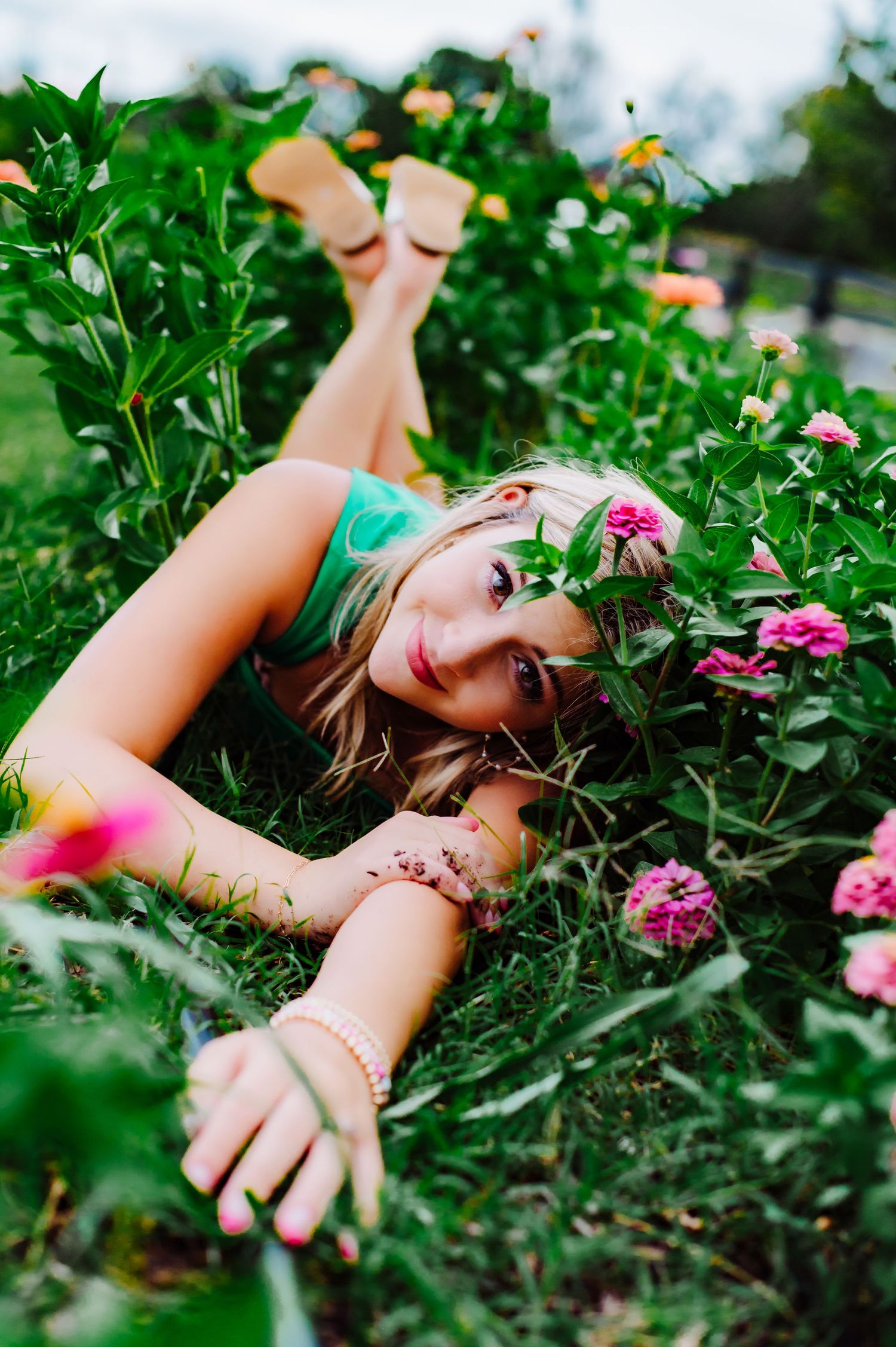 Creative photo shoot among pink flowers and green foliage with artistic poses.