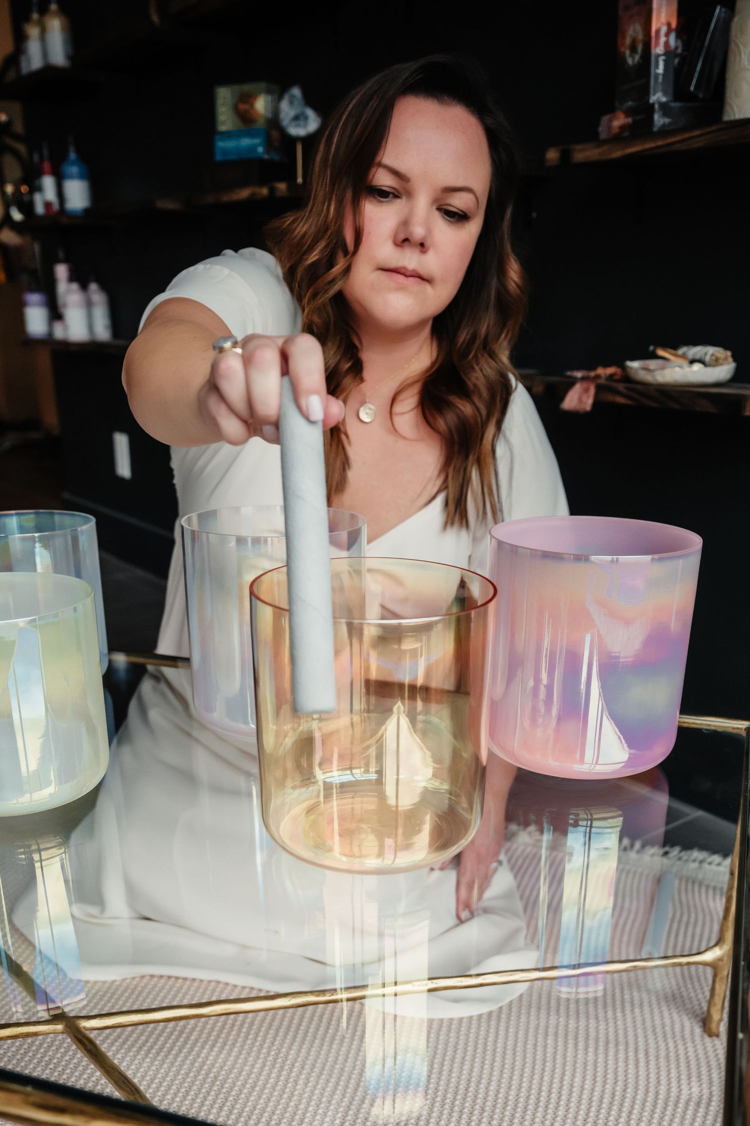 Someone pouring drinks into iridescent glasses on a mirrored tray.