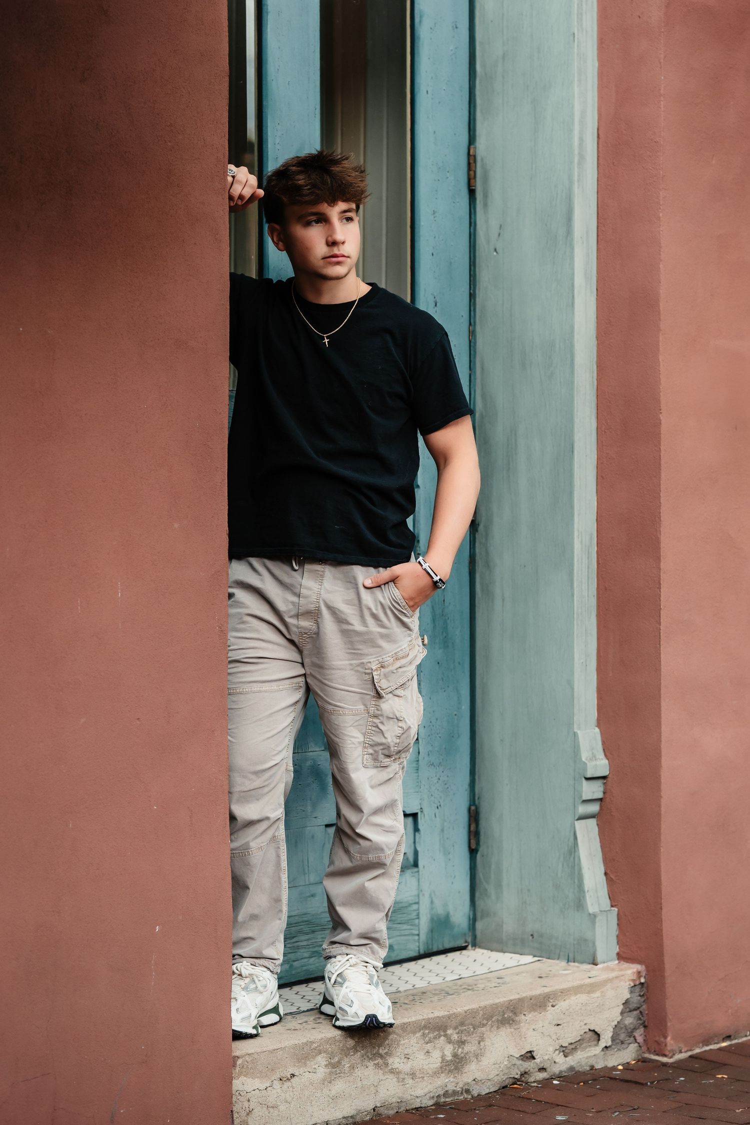 A casual portrait against turquoise and coral walls in an urban setting.