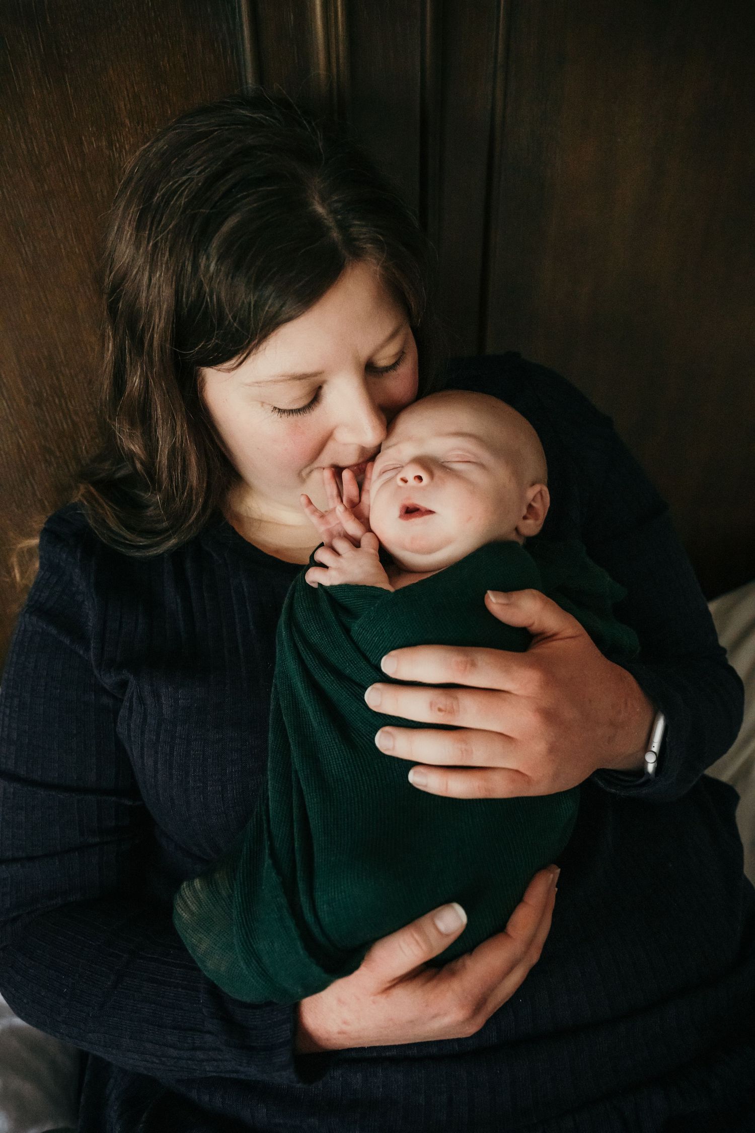 An intimate moment between parent and infant in dark moody lighting.