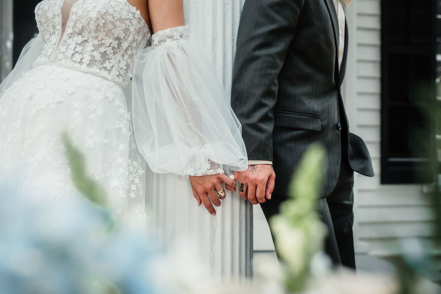 Close up detail of a couple's hands touching during an elegant outdoor wedding ceremony in white and black attire.