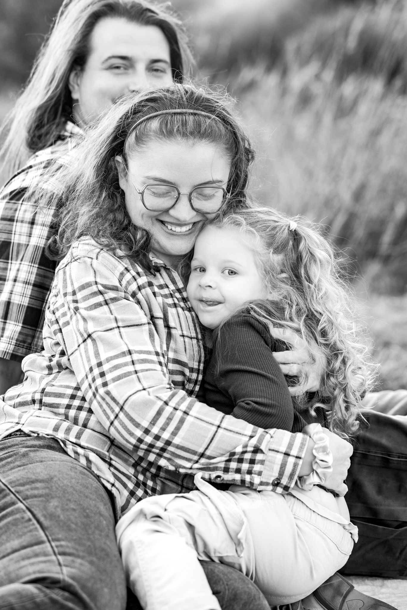 A tender black and white portrait showing an intimate family moment together outdoors.