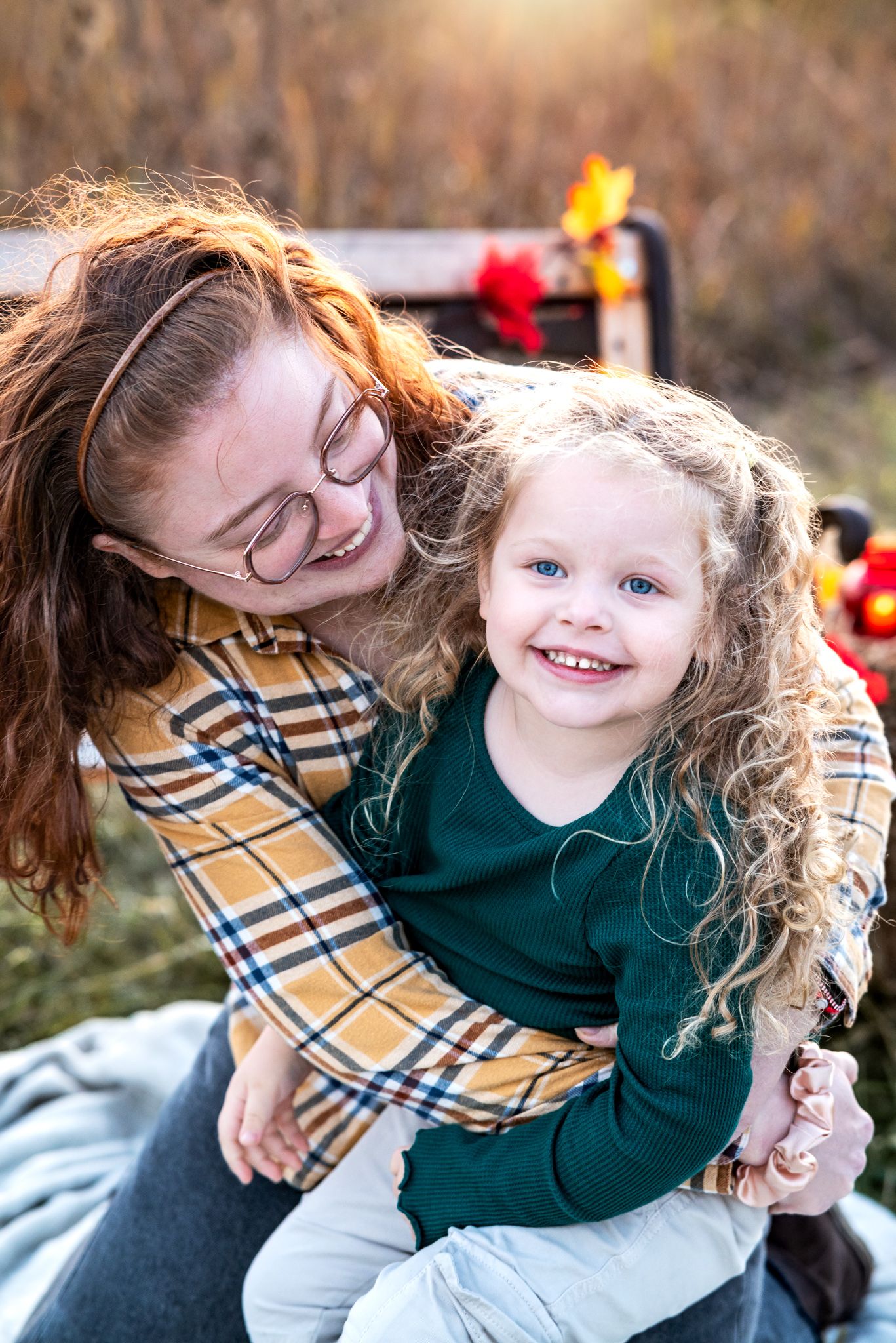 A joyful embrace outdoors features a plaid shirt and cozy green sweater on a sunny autumn day.