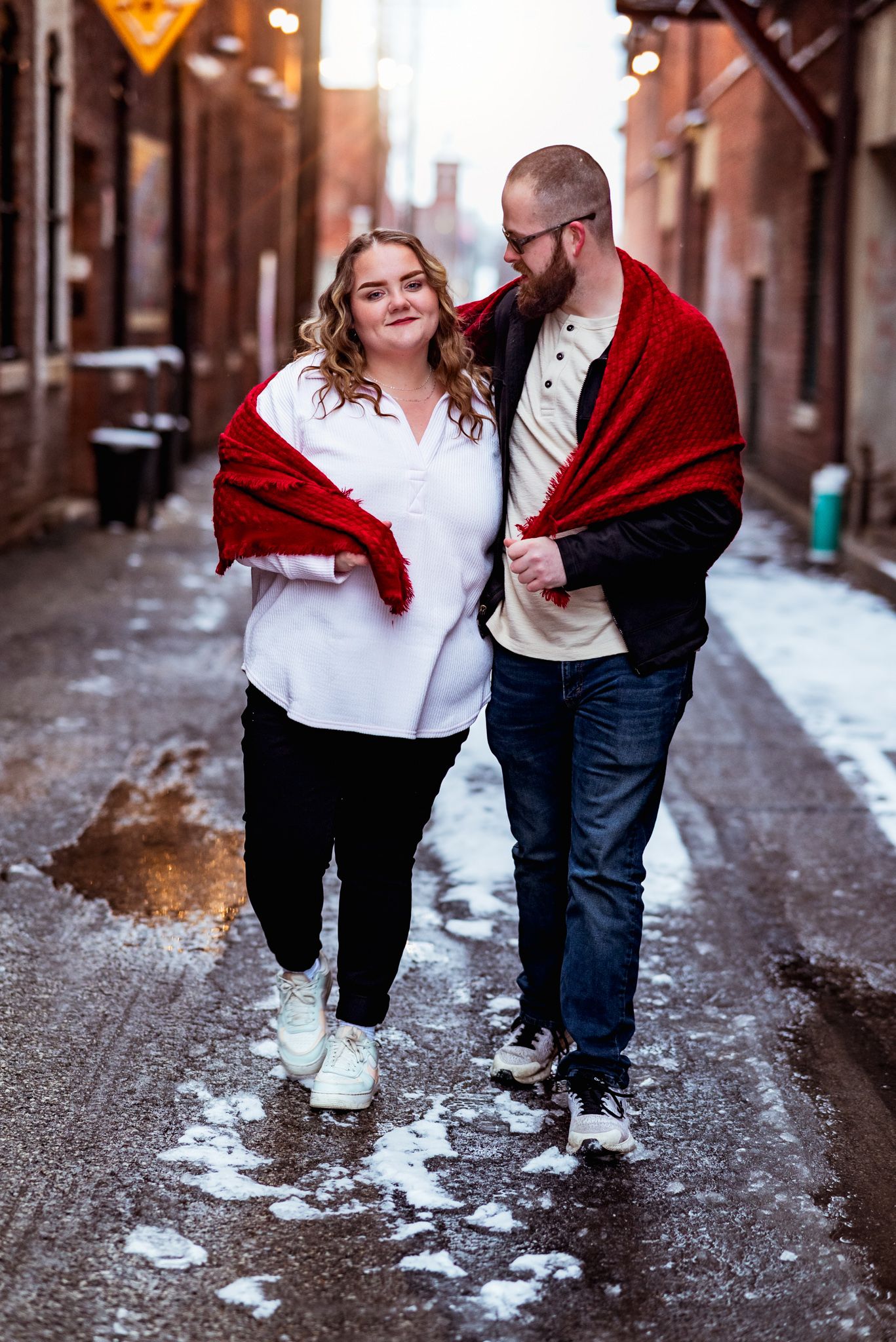 Couple walking together in an urban alley with snow on the ground, shown in a series of romantic candid moments.