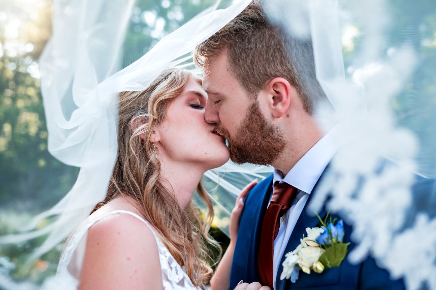 A romantic wedding couple shares intimate kisses in a dreamy outdoor setting with soft lighting and floral details.