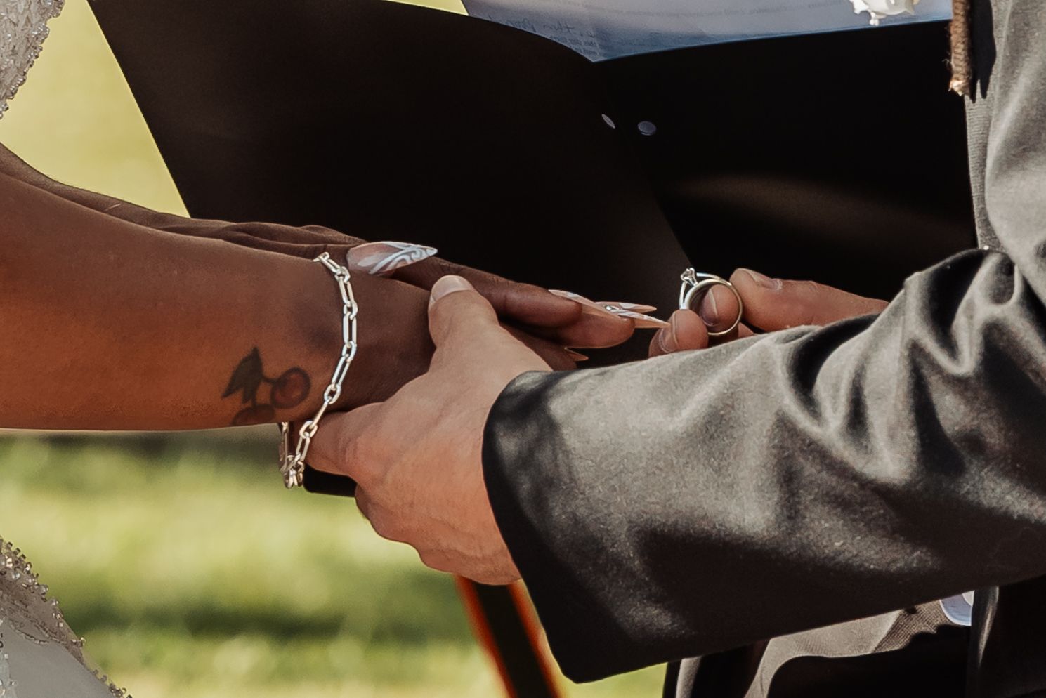 The groom placing the ring on the brides finger at an outdoor wedding.