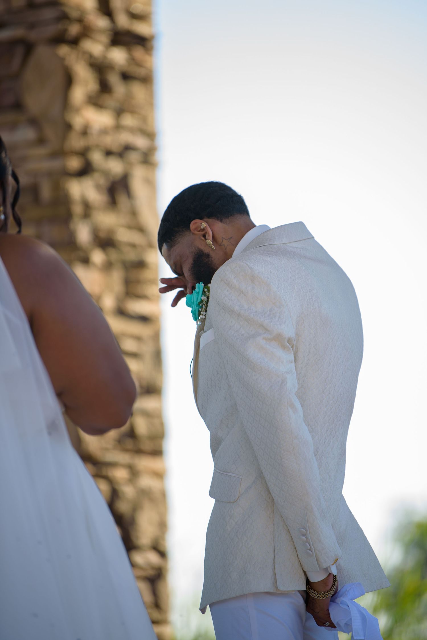 Wedding ceremony moments captured against stone wall backdrop during sunset.