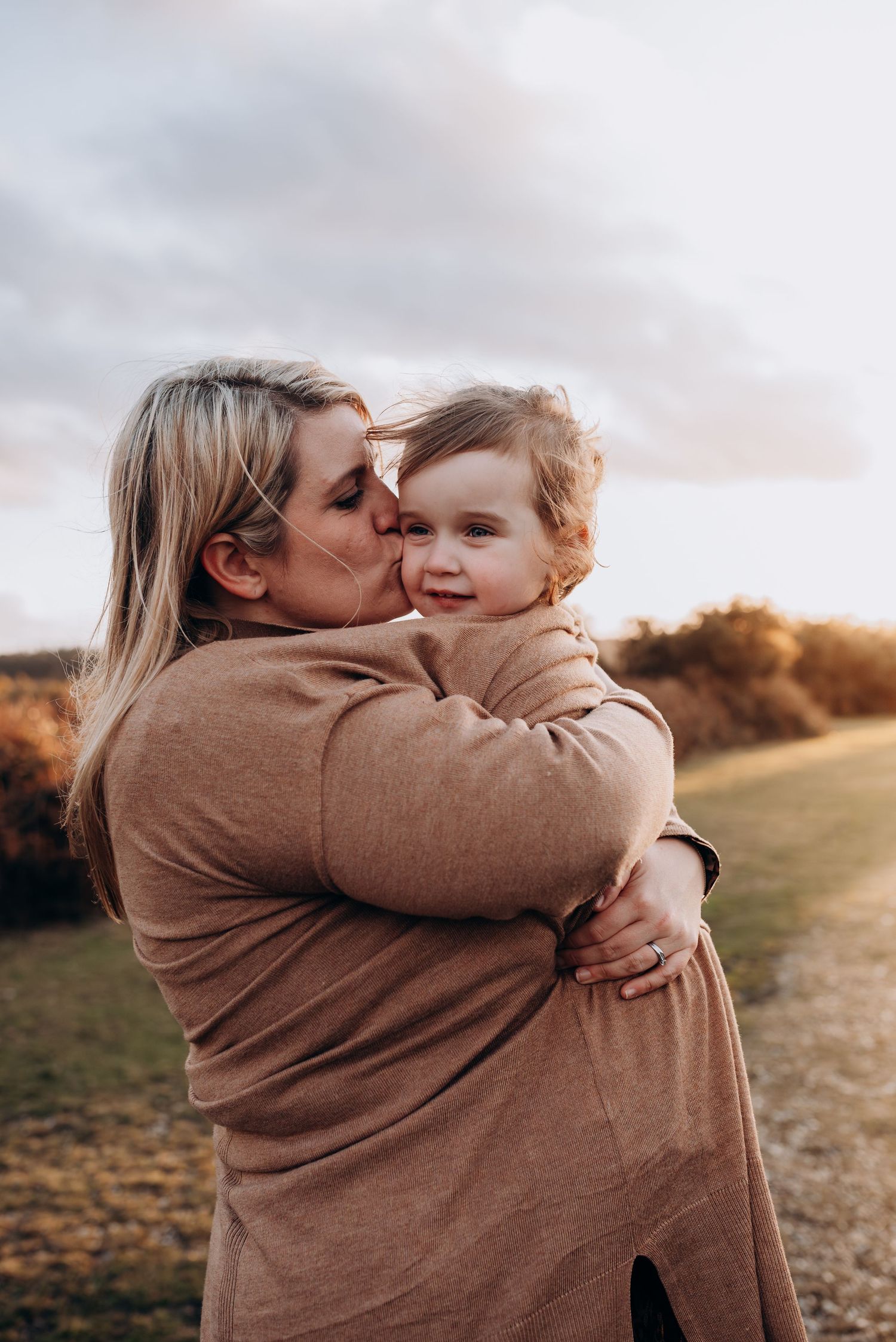 A tender moment of affection and hugs captured outdoors at sunset.