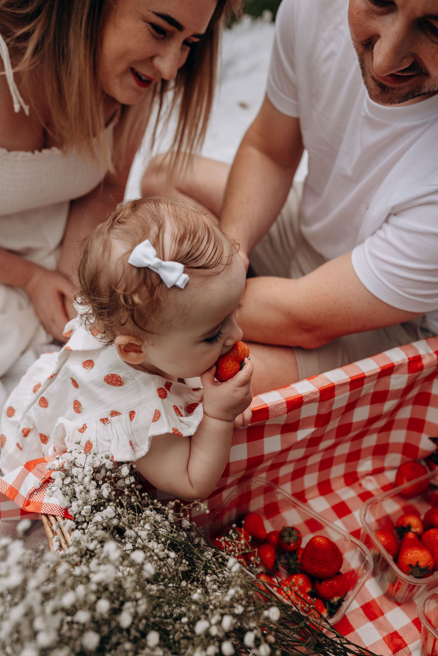A picnic scene with a red and white checkered blanket and white flowers.