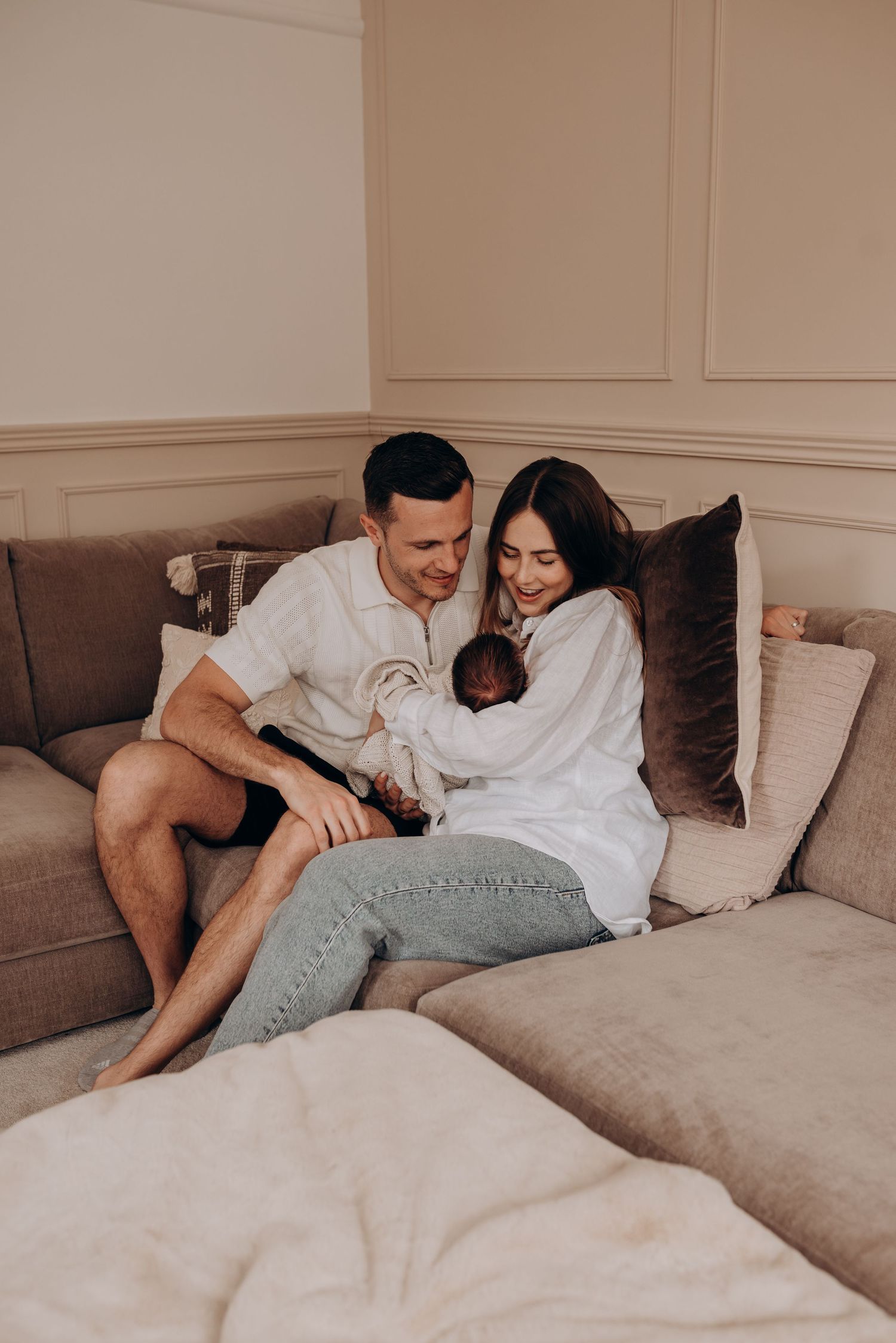 A cozy family moment on a brown couch with a newborn baby.