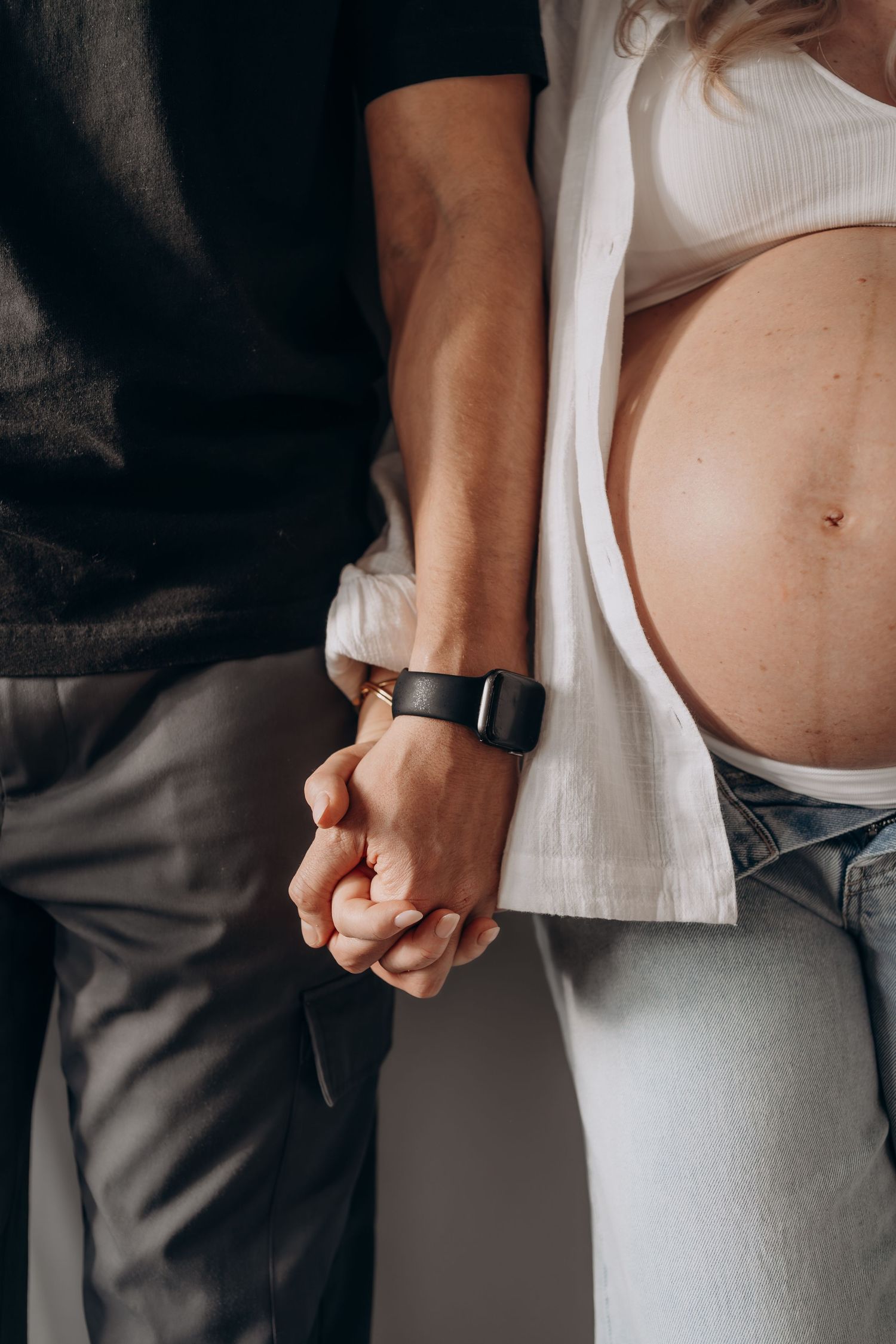 A series of minimalist pregnancy progression photos showing a growing belly against white and gray clothing.