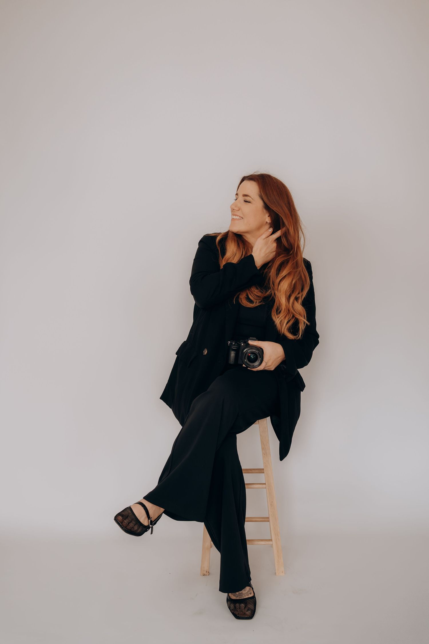 A person in a black suit sits on a wooden chair against a white wall, shown in a series of dynamic poses.