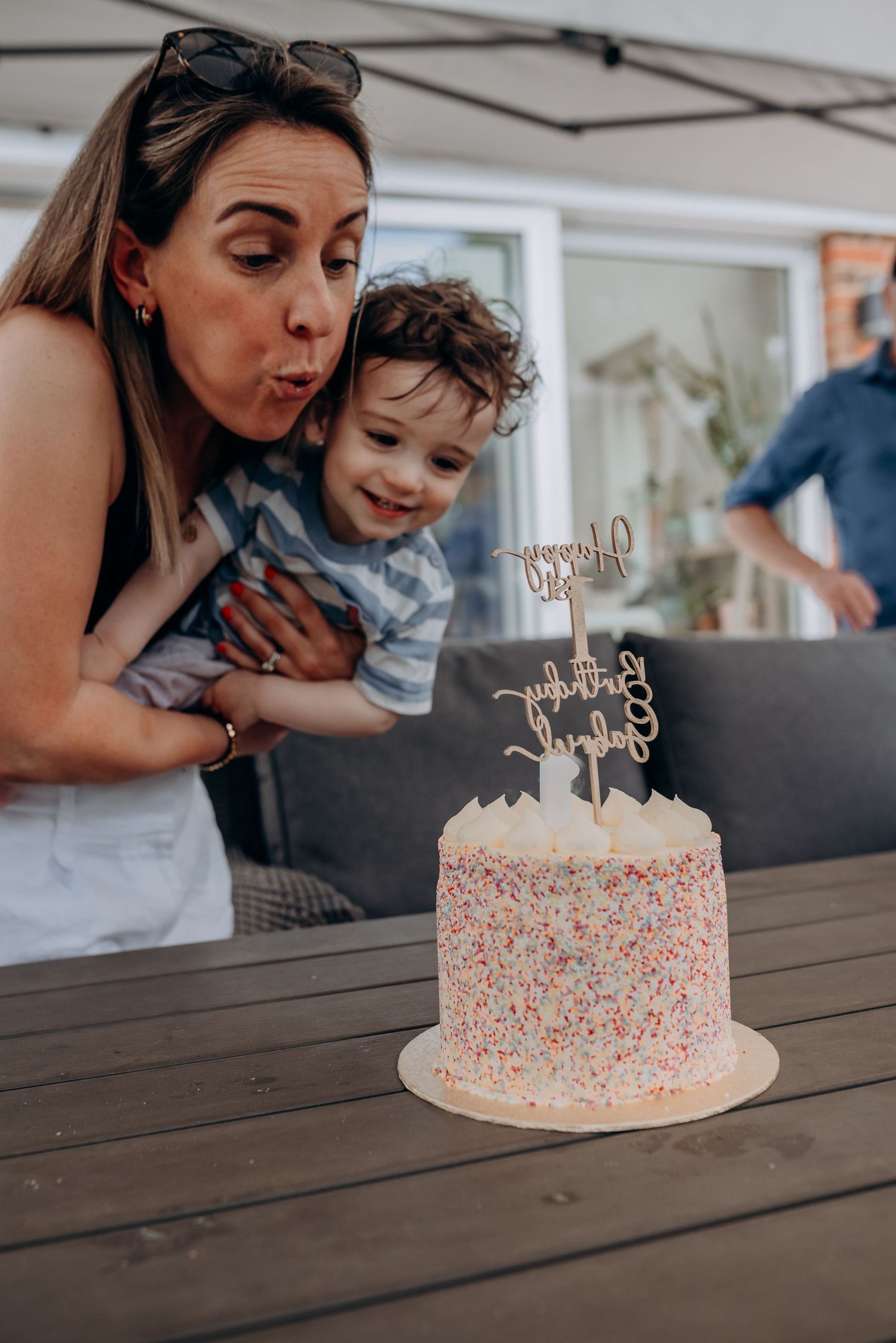 Looking down at a birthday cake with pink sprinkles on wooden table.