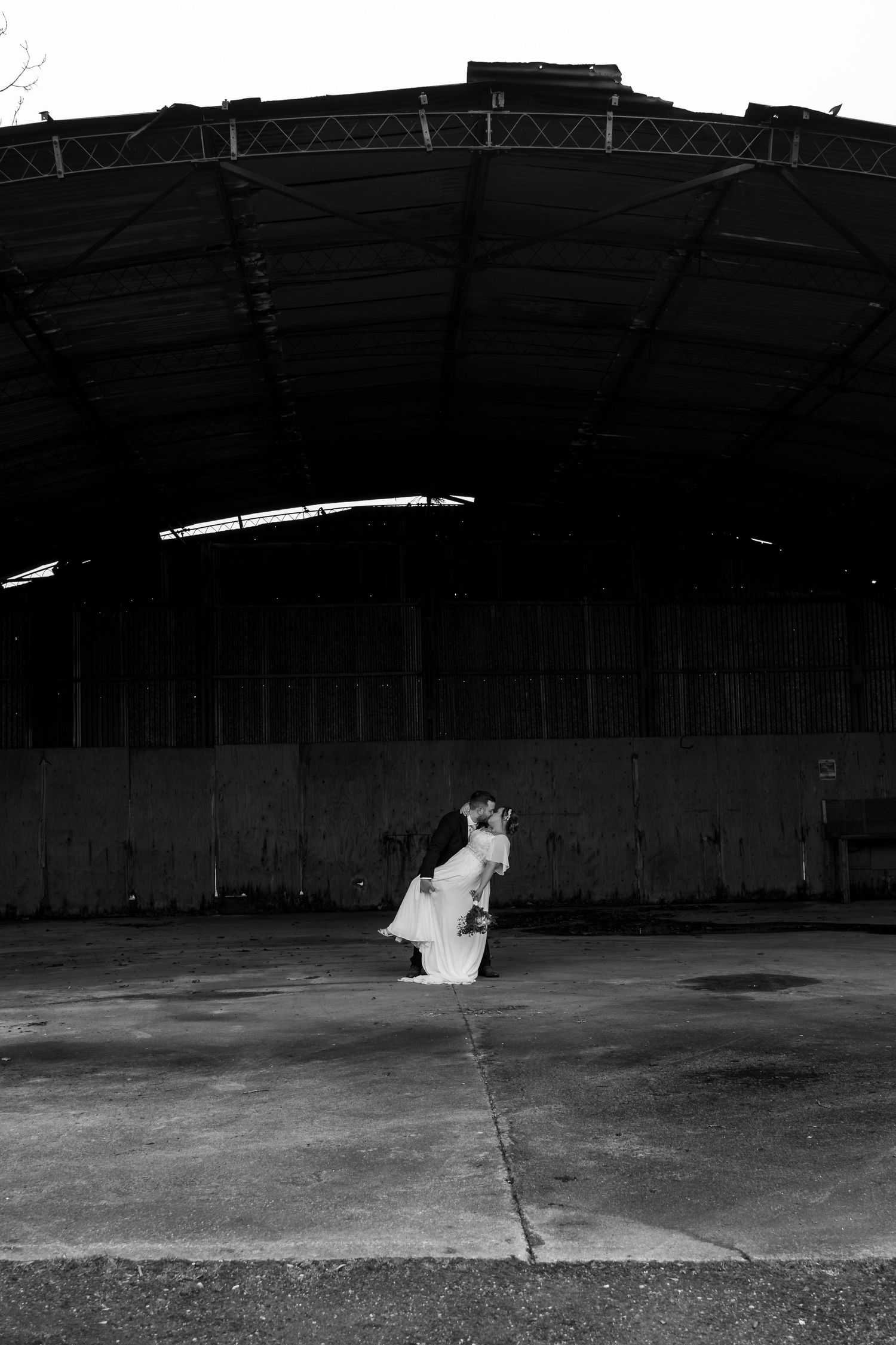 A sequence of black and white photos showing a figure in white moving across a dark empty warehouse space.