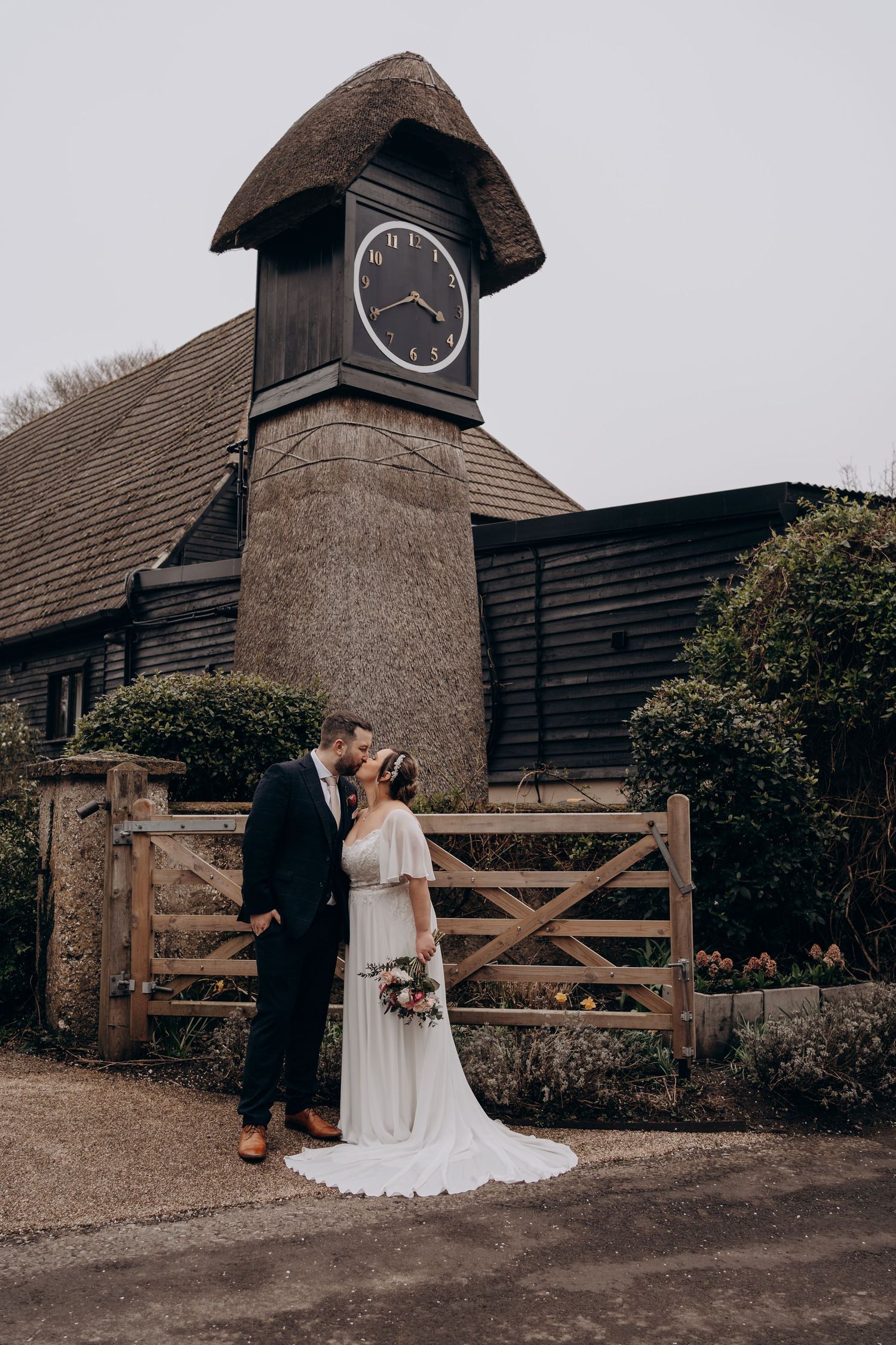 A romantic wedding couple poses in front of a rustic barn with wooden gates in a series of artistic shots.