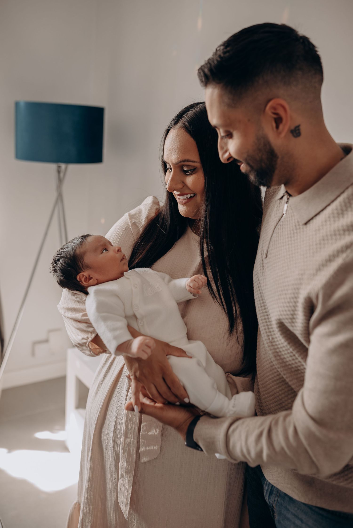A tender family moment with a newborn baby in a bright, minimalist room.