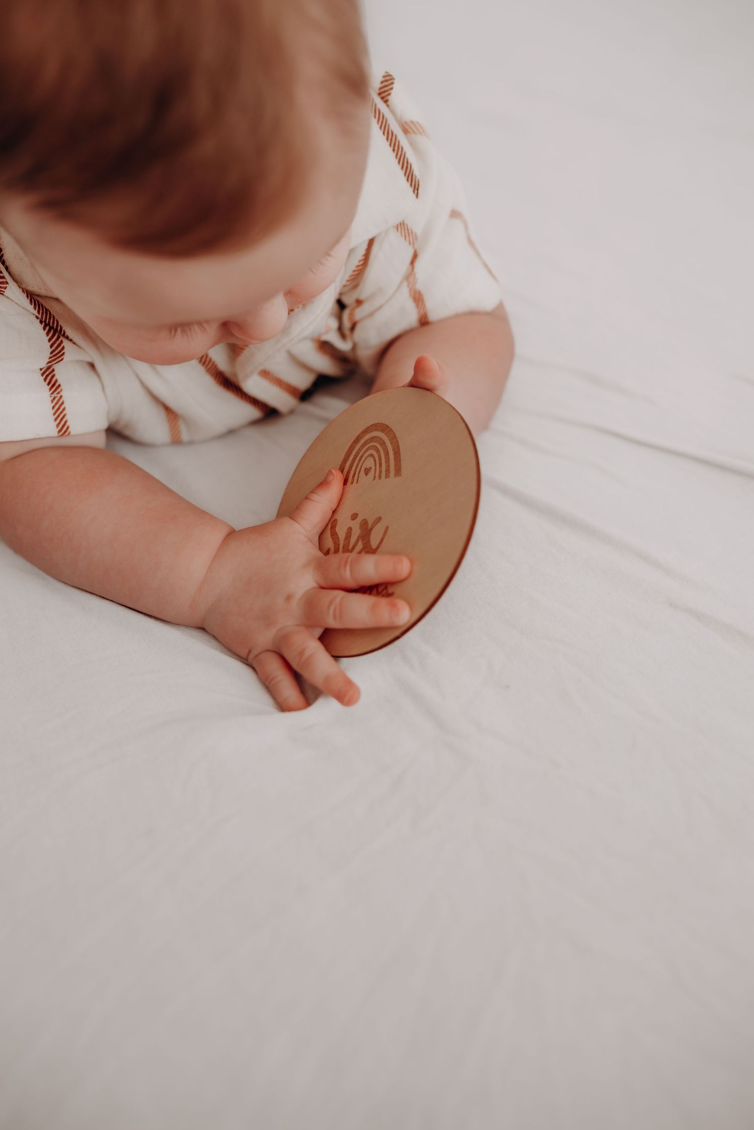 Close-up view of small hands holding a wooden toy against a white background.