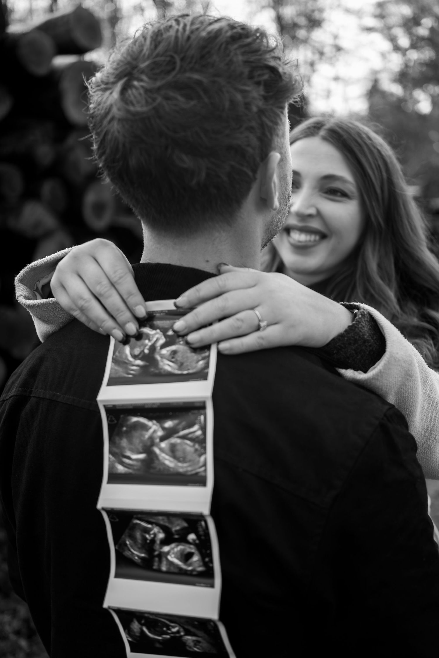 A black and white photo sequence shows a couple embracing while holding and looking at ultrasound photos together.