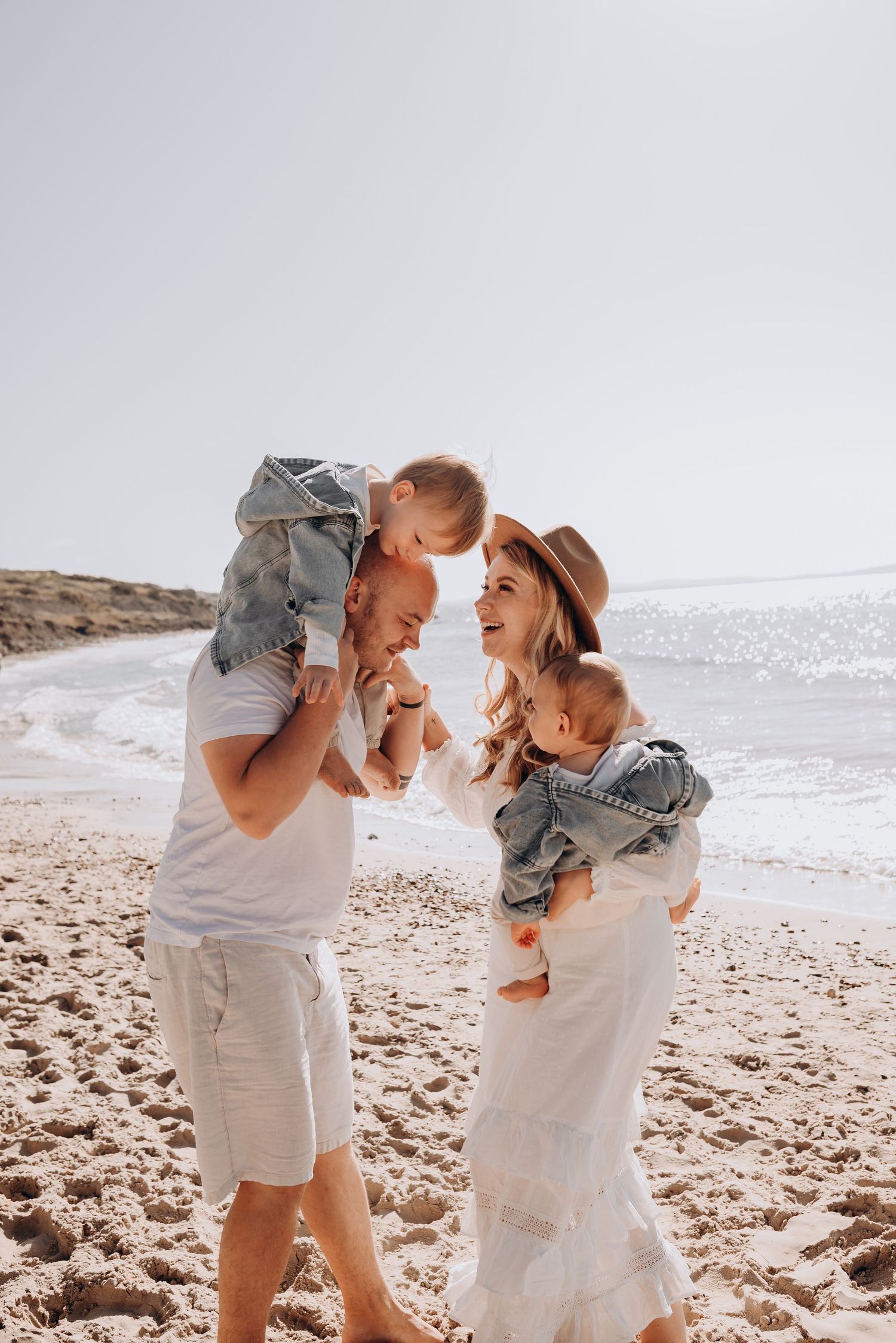 A family plays together on a sunny beach with waves in the background.