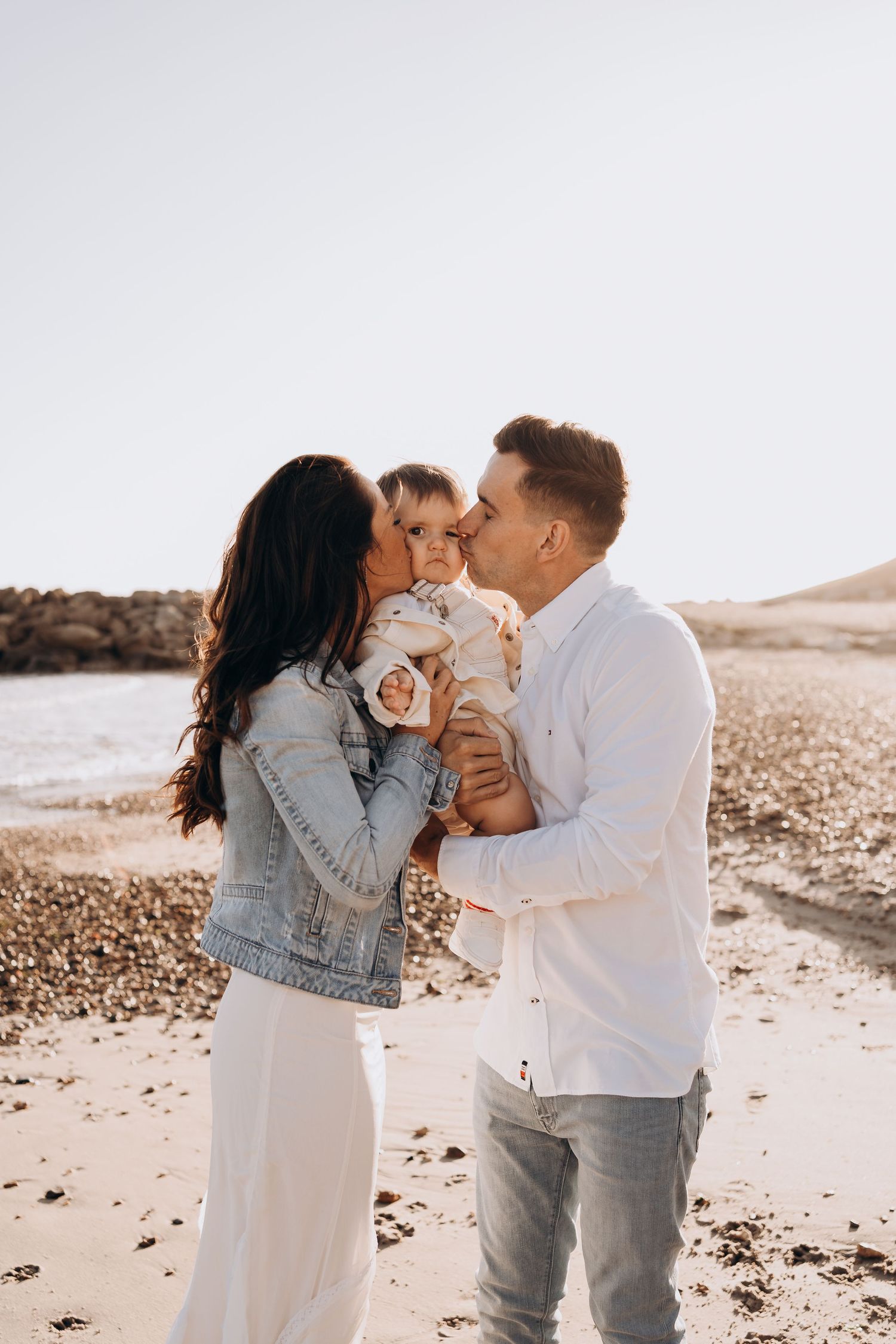 Family sharing tender moment on beach during golden hour.