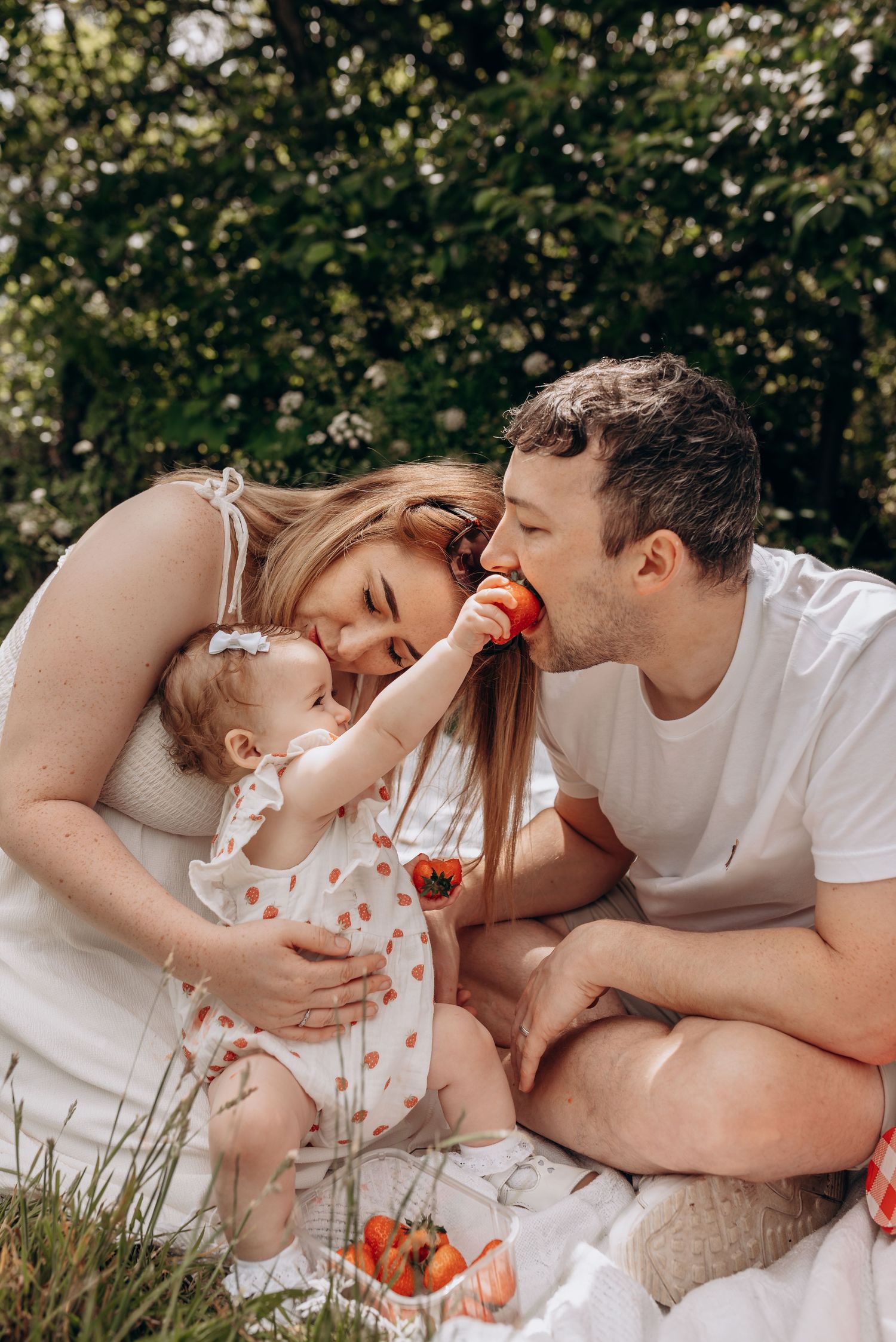 Family enjoying a picnic together on a sunny day with strawberries.