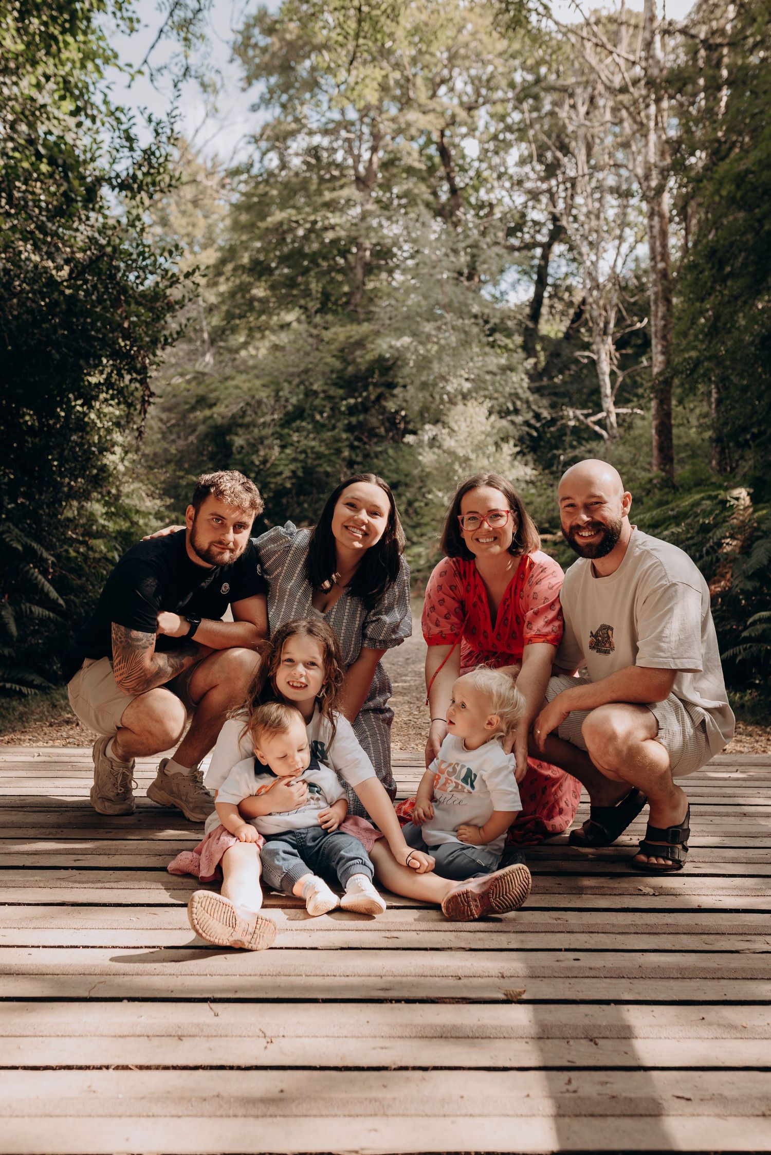 Group of friends and family relaxing together on wooden deck in forest setting.