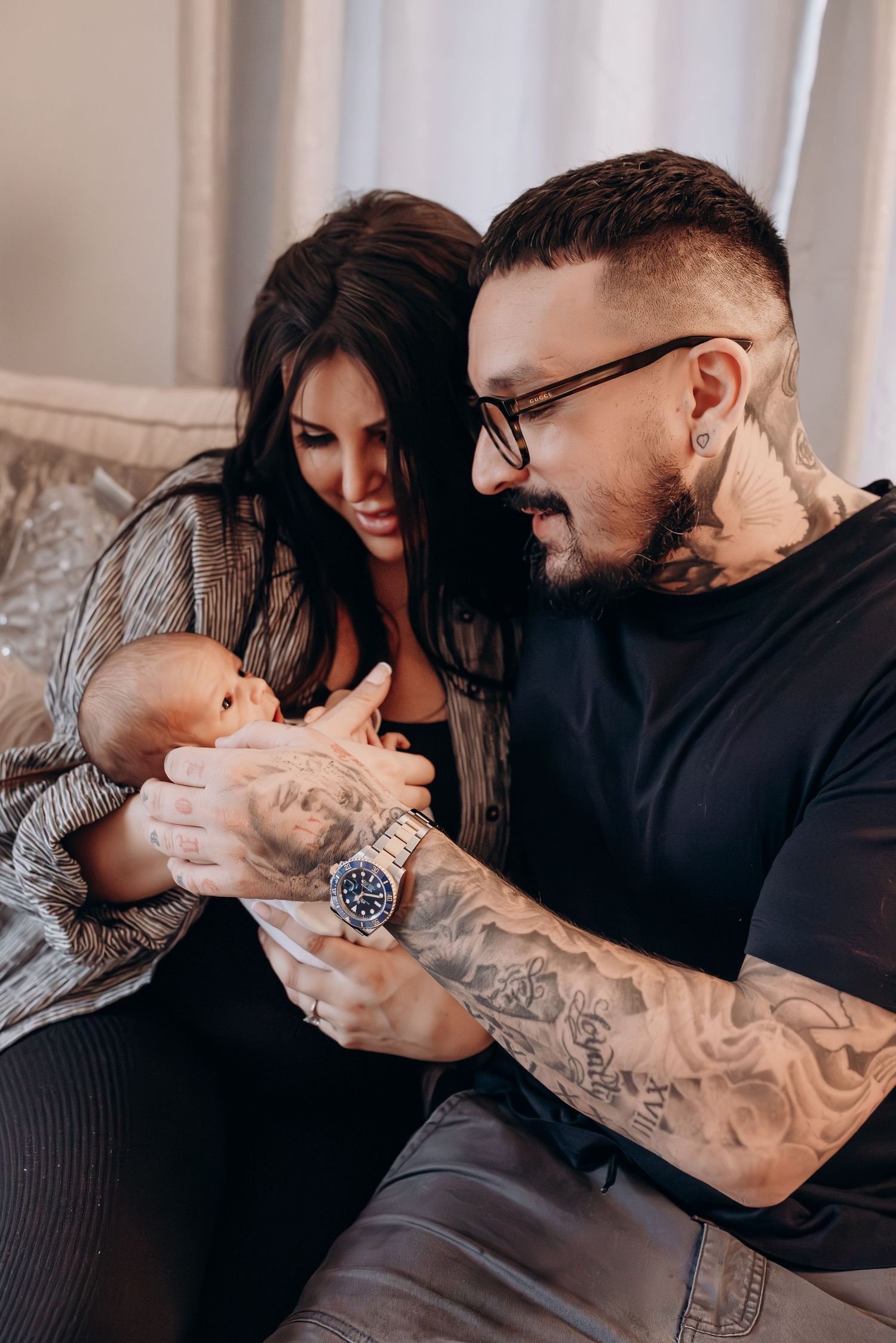 Family on grey couch sharing intimate moments with their newborn baby.