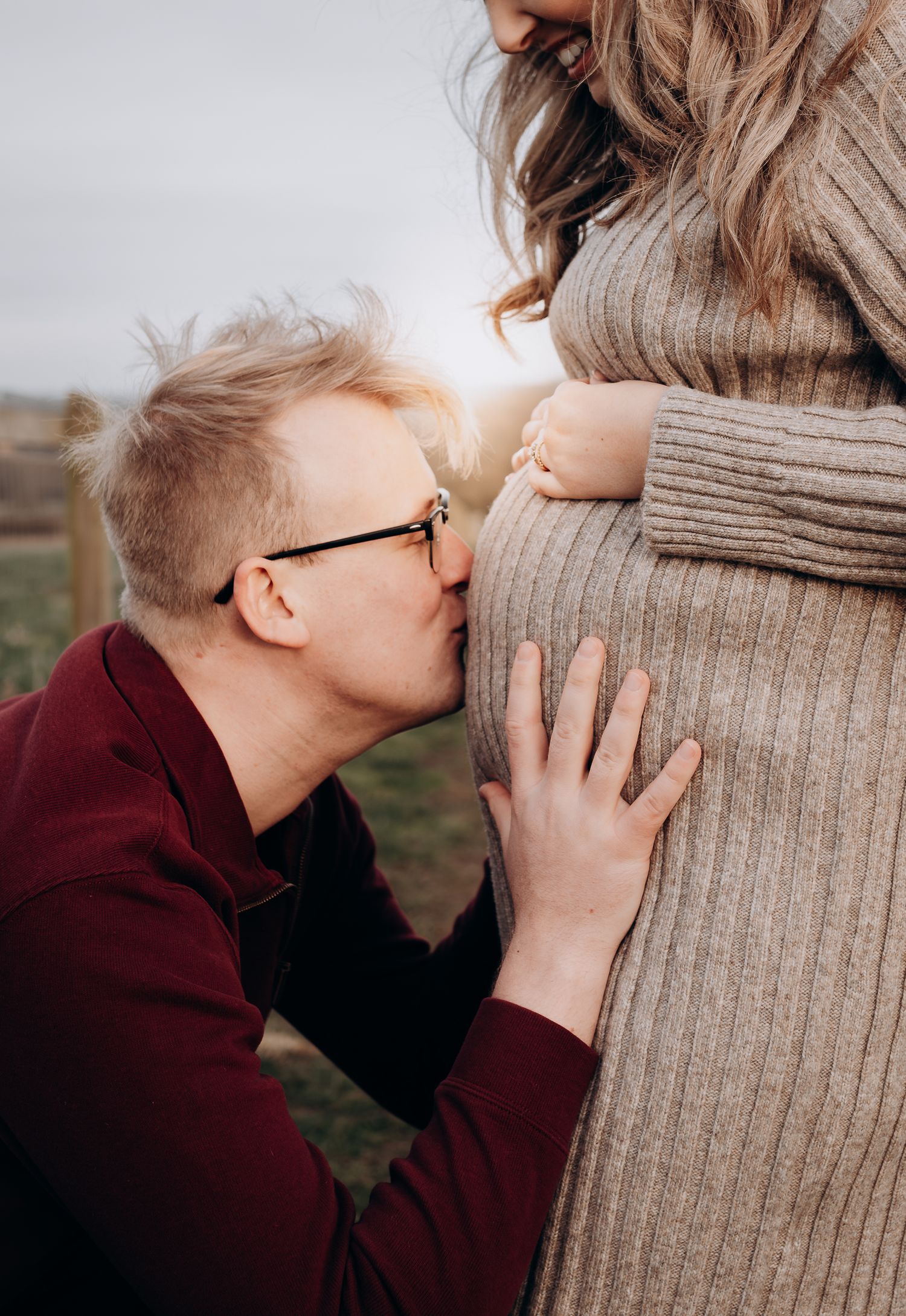 An intimate maternity moment captured in soft winter light outdoors.