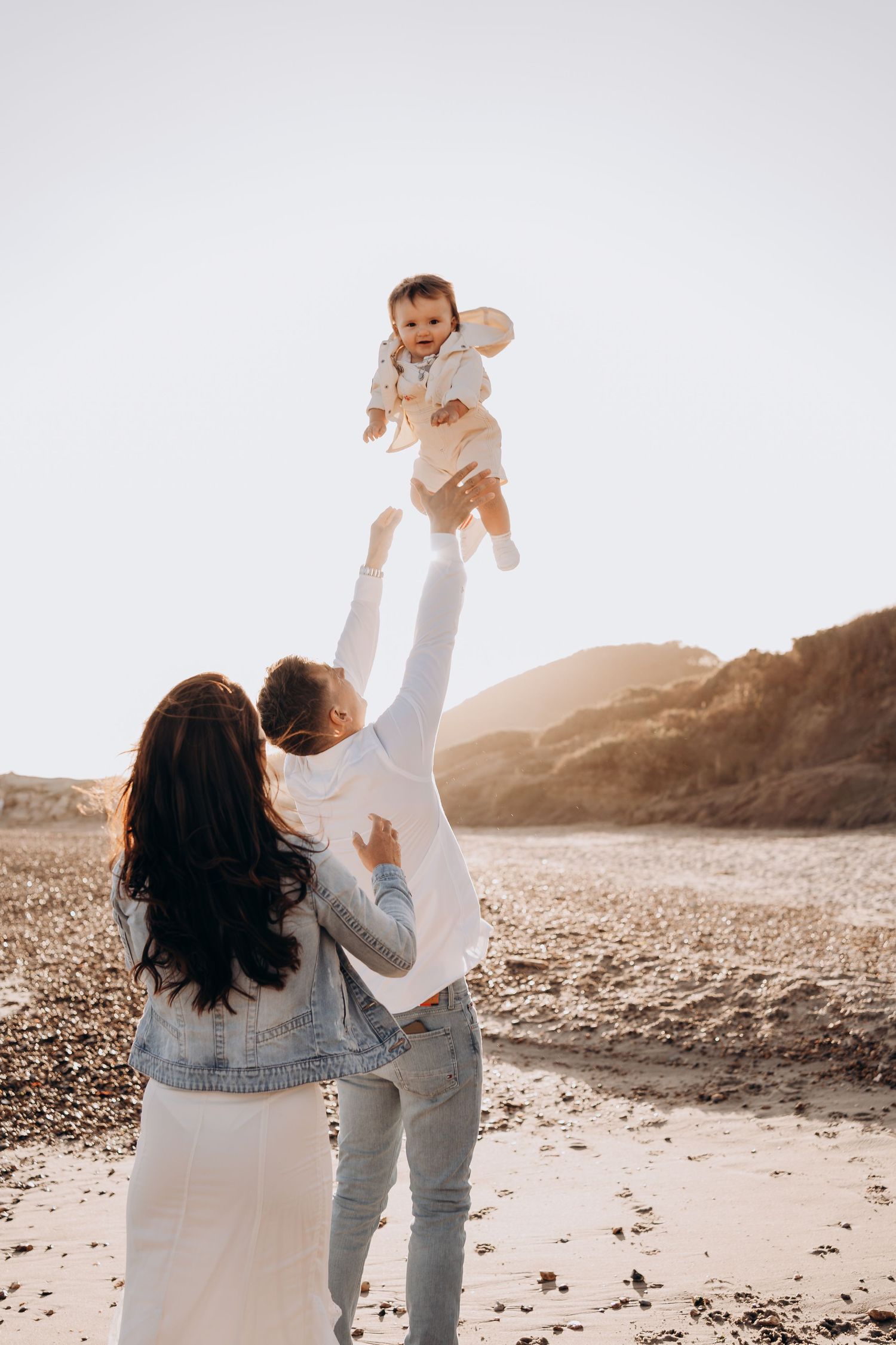 A family plays together on a beach during golden hour.