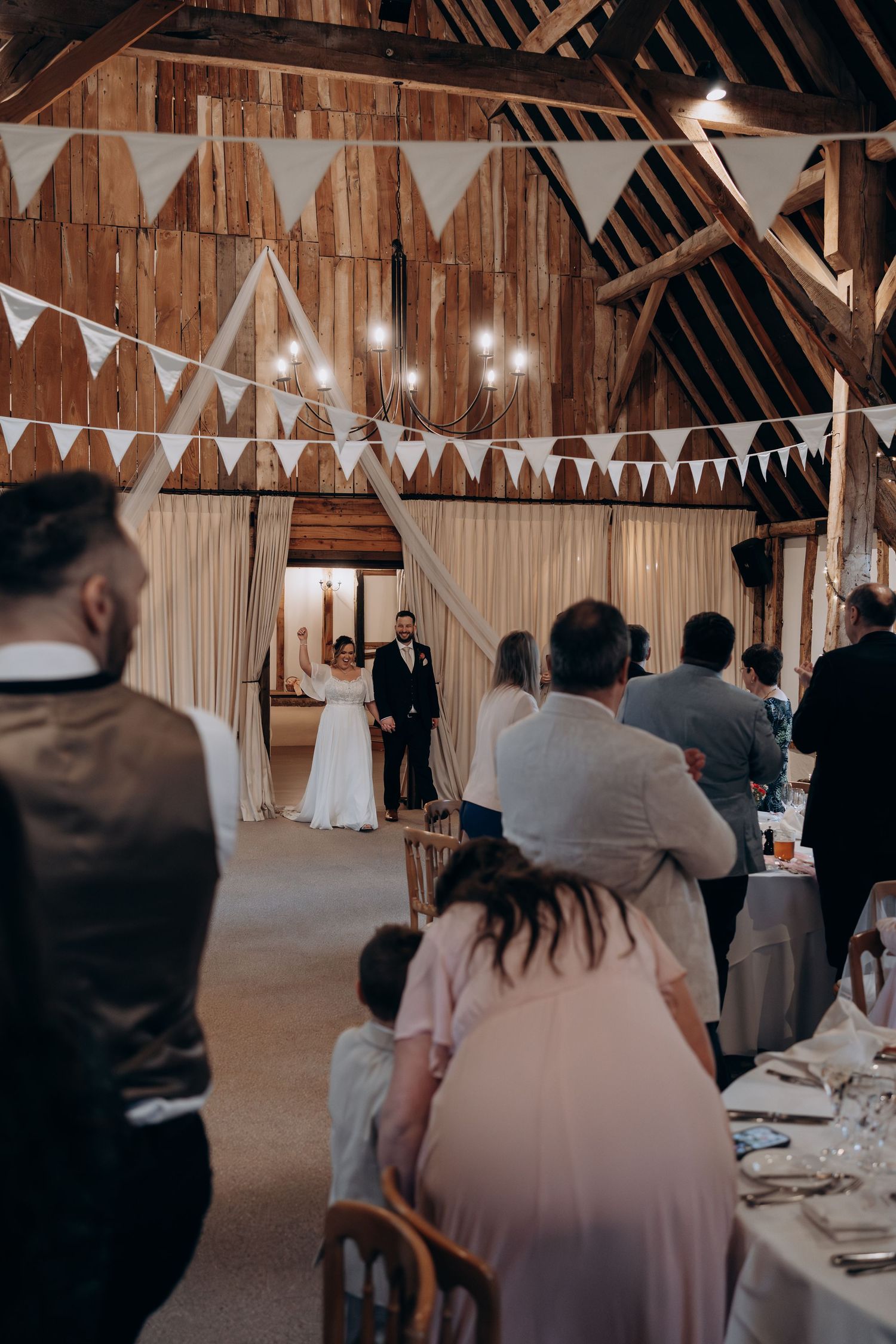 A rustic barn wedding reception venue decorated with white bunting banners and string lights creating a cozy atmosphere.
