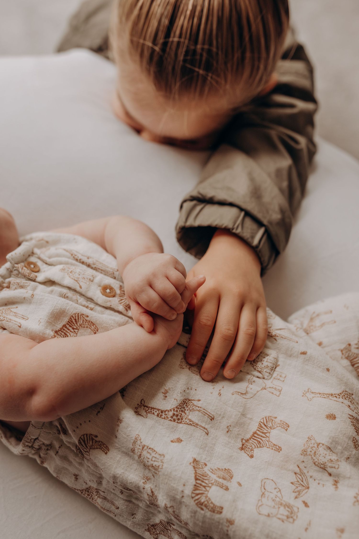 Close-up of small hands touching patterned fabric in muted tones.