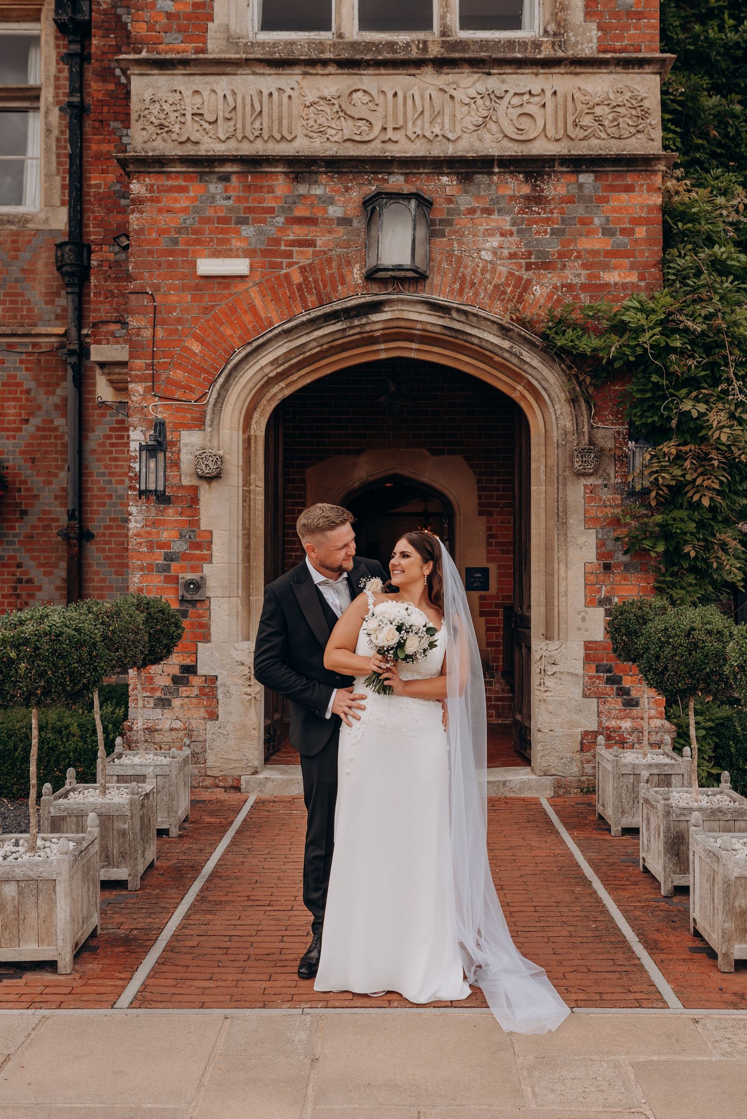 A romantic wedding photoshoot series in front of a historic brick building with stone archways and steps.