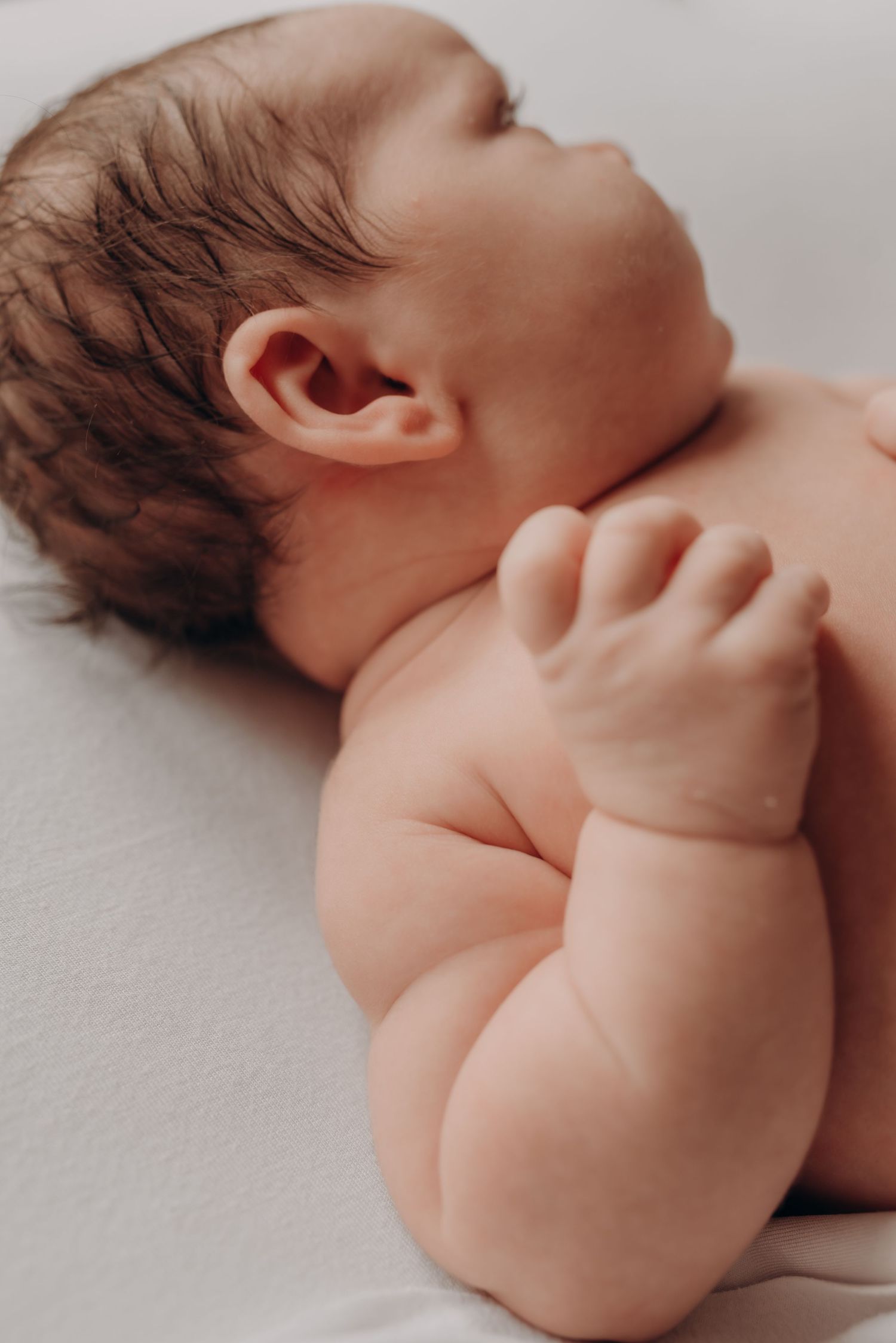 Close-up view of a sleeping infant against soft white bedding.