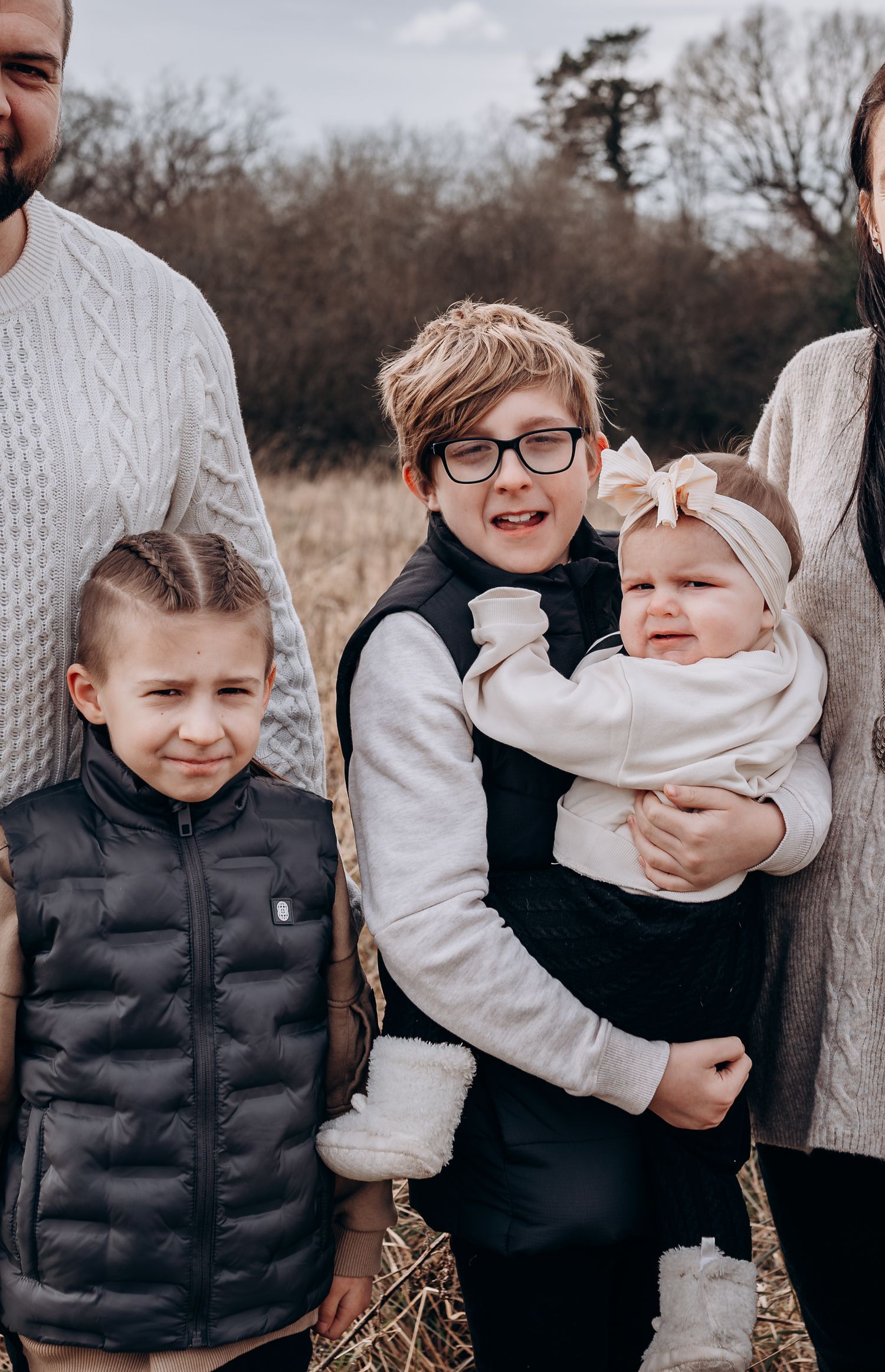 Family members in winter clothing posing together in natural setting.