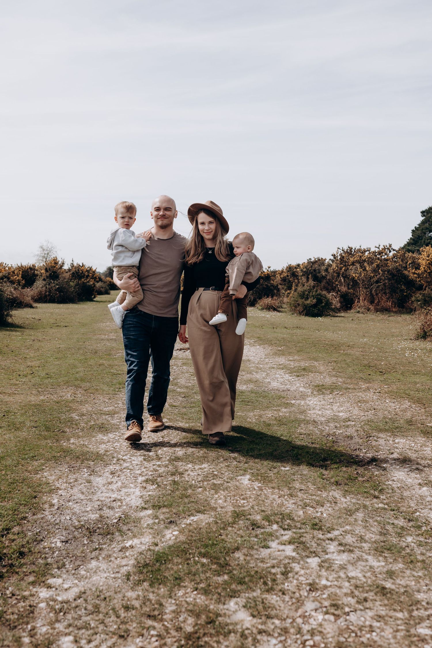 Family walking together on a dirt path through an open field.