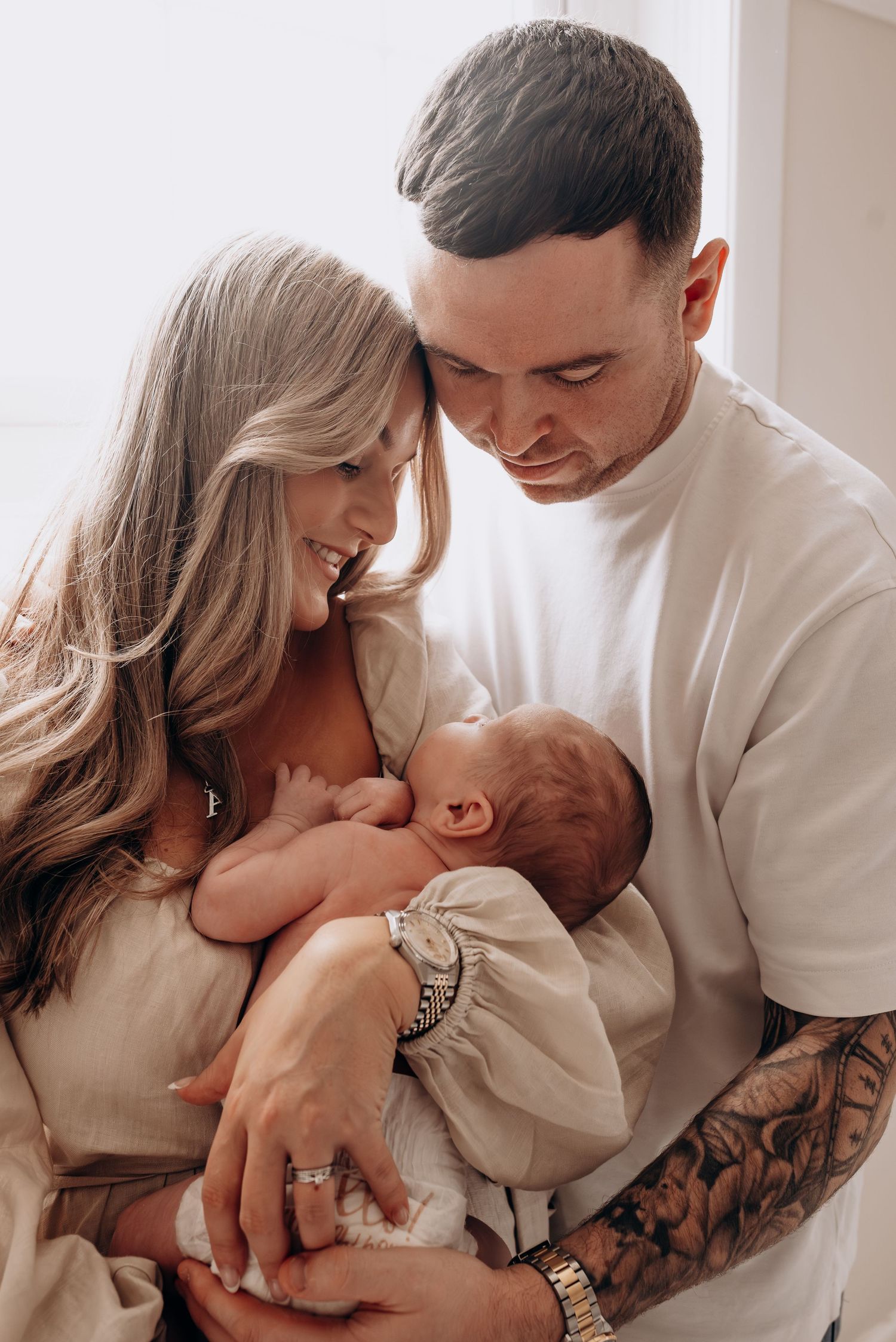 A loving couple shares tender moments with their newborn baby in a series of intimate lifestyle photos.