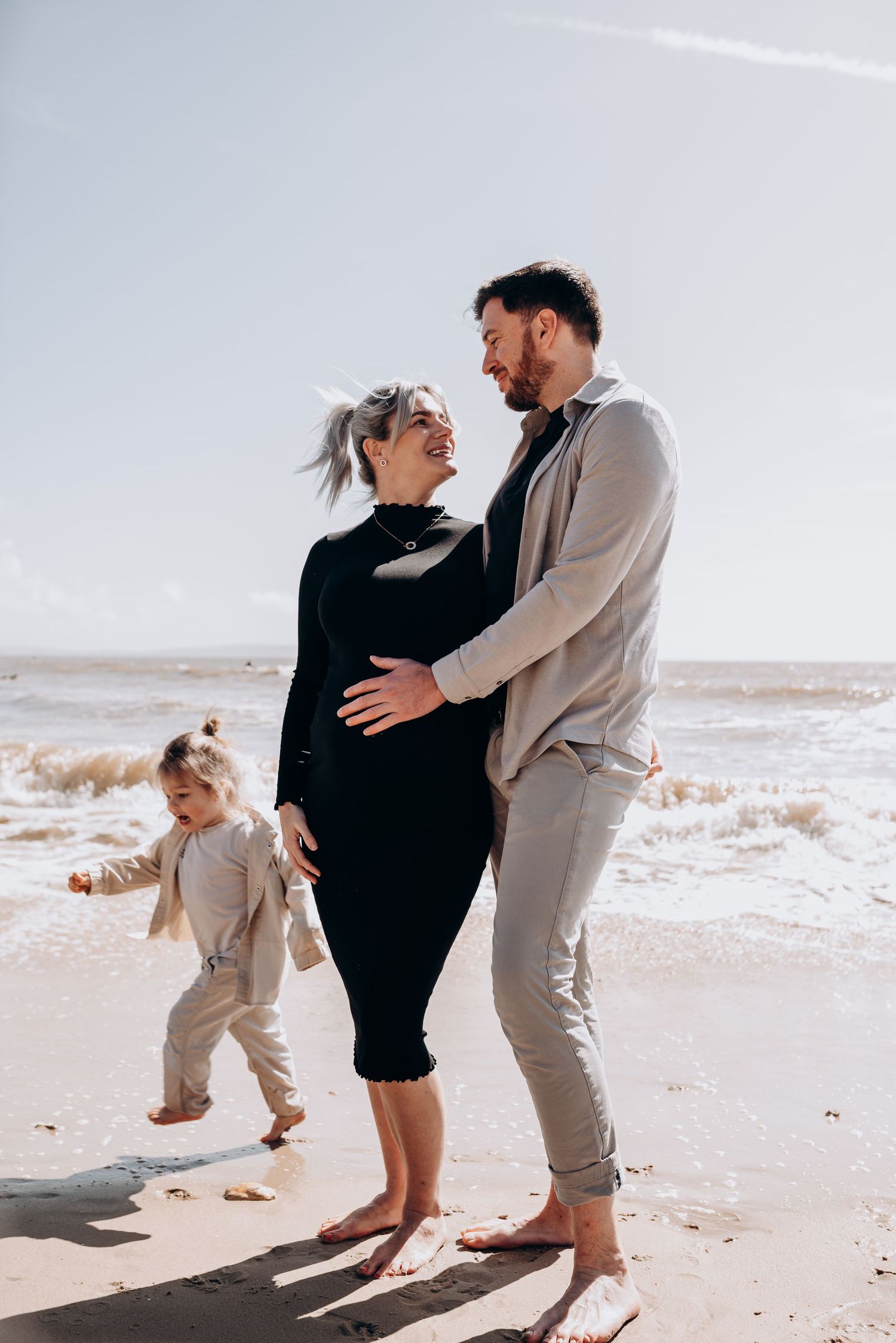 A playful family photo session at the beach with light neutral clothing.