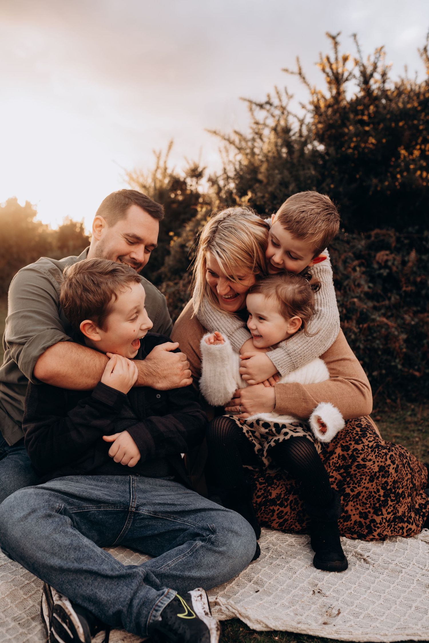 Candid family moments showing playful interactions on a blanket outdoors.