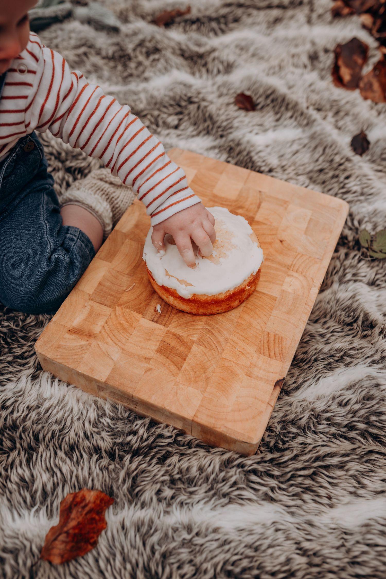 Hands kneading dough on a wooden cutting board over furry rug.