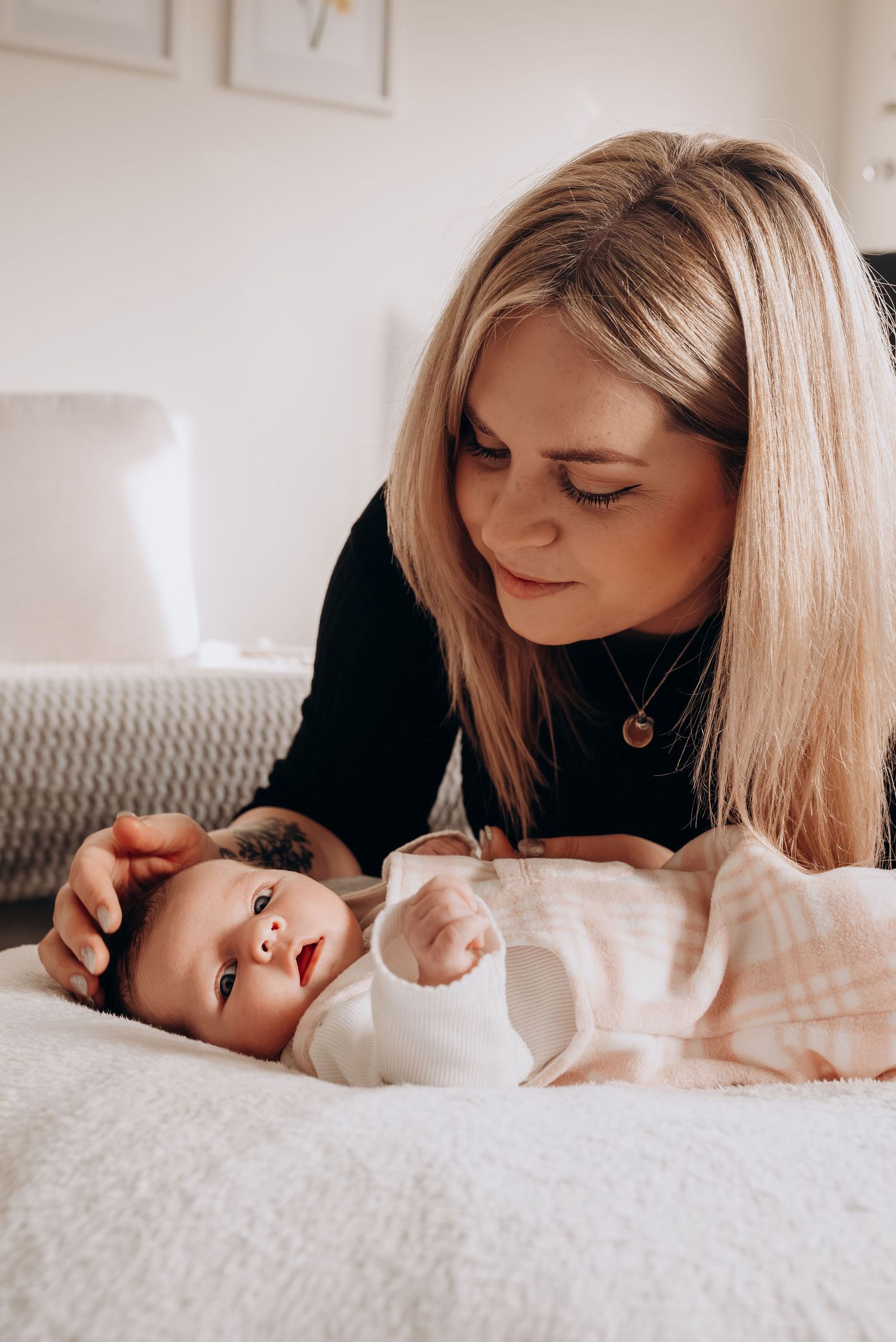 A tender moment between parent and baby lying together on a soft white surface.