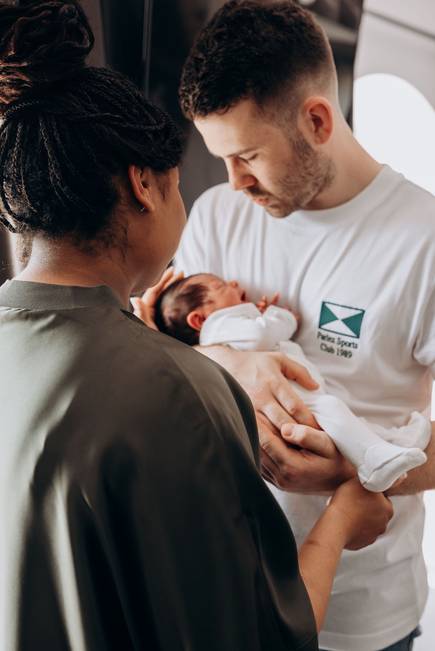 A touching scene of a parent in a white t-shirt holding and bonding with their newborn baby.