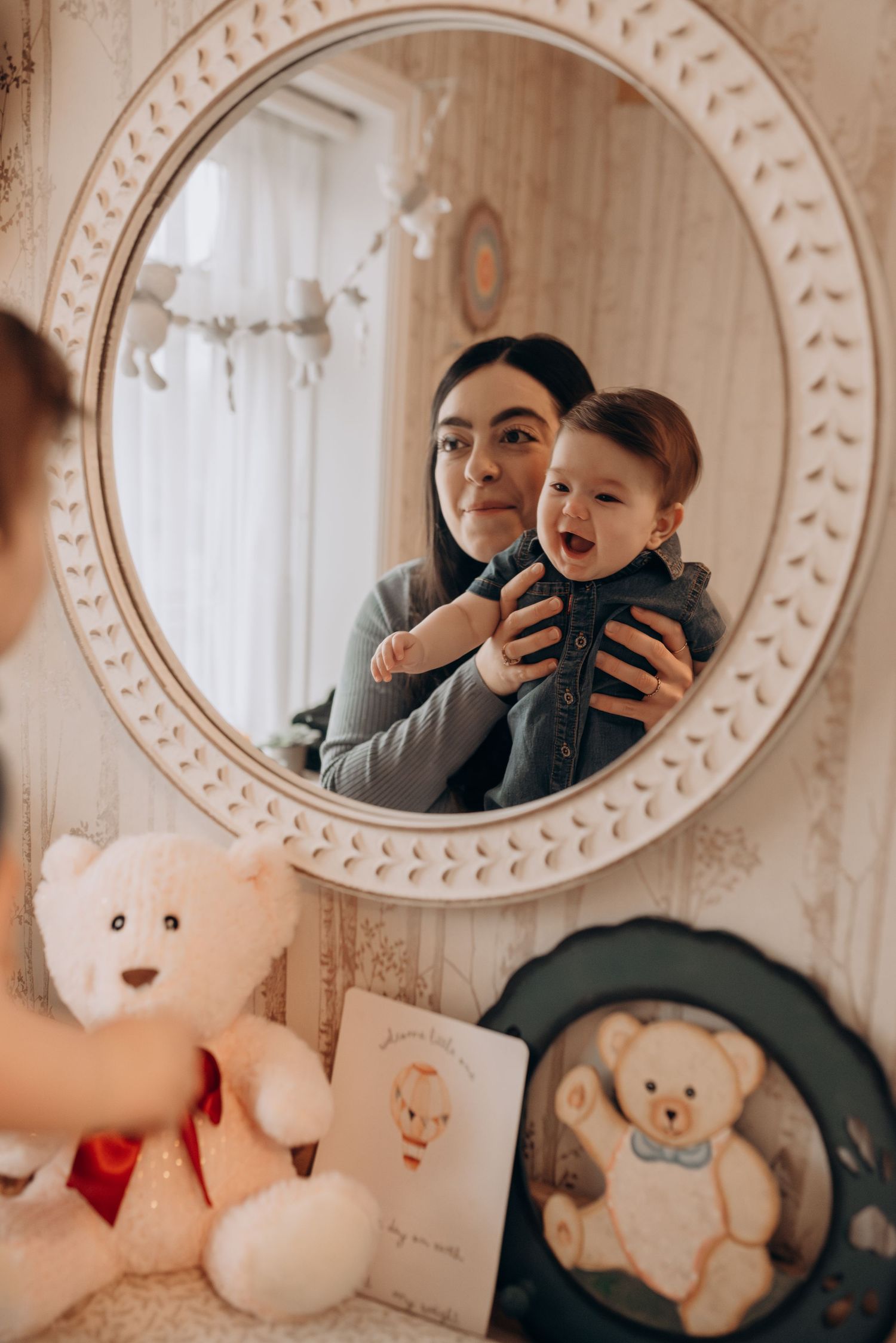 Reflection in oval mirror shows plush toys and decorative elements arranged for a photo session.